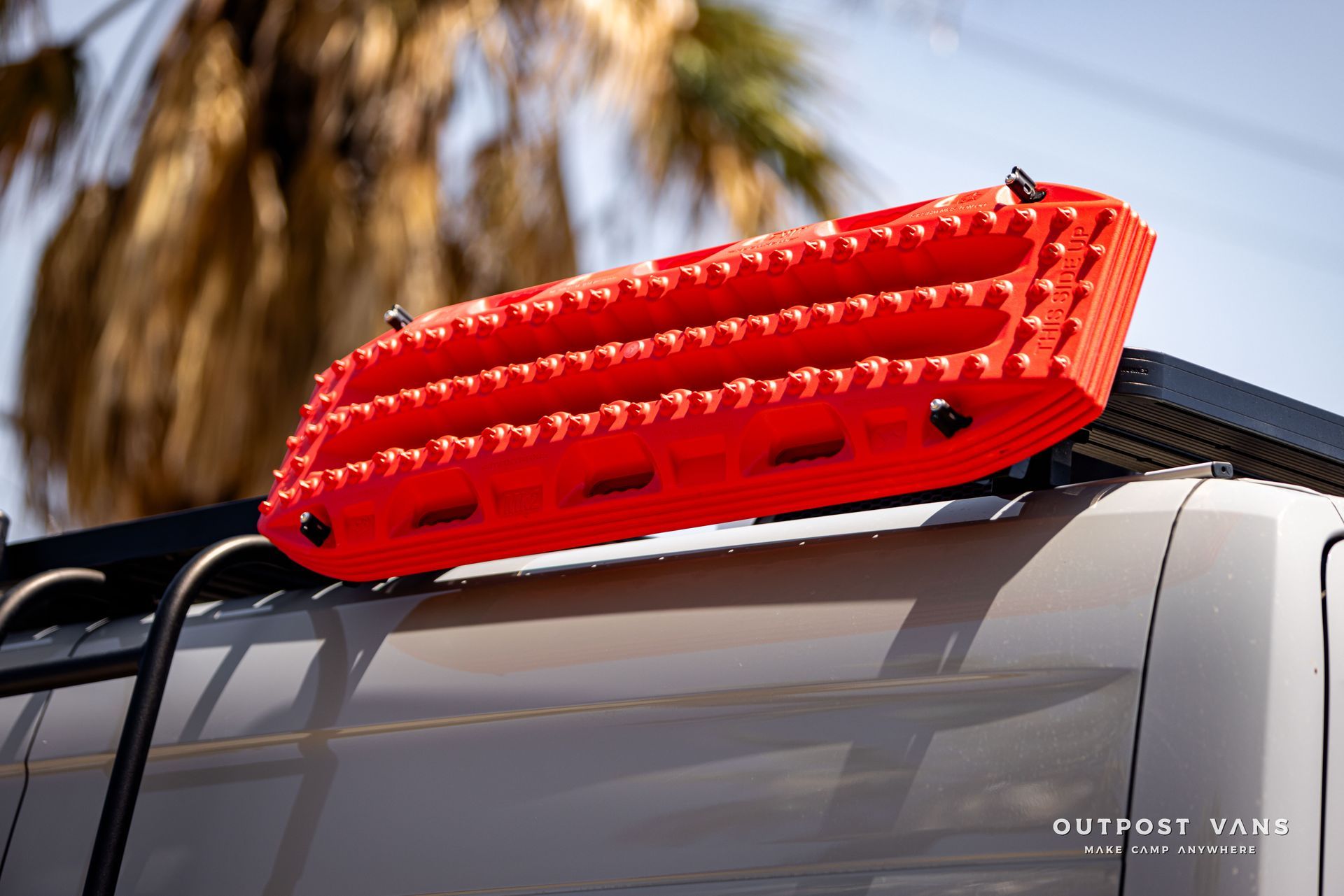 A red raft is attached to the roof of a vehicle.