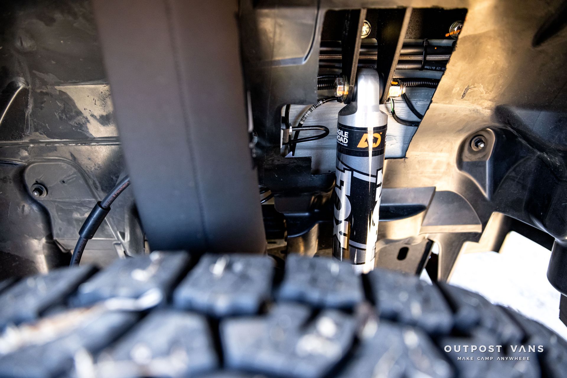 A close up of a shock absorber and a tire on a truck.