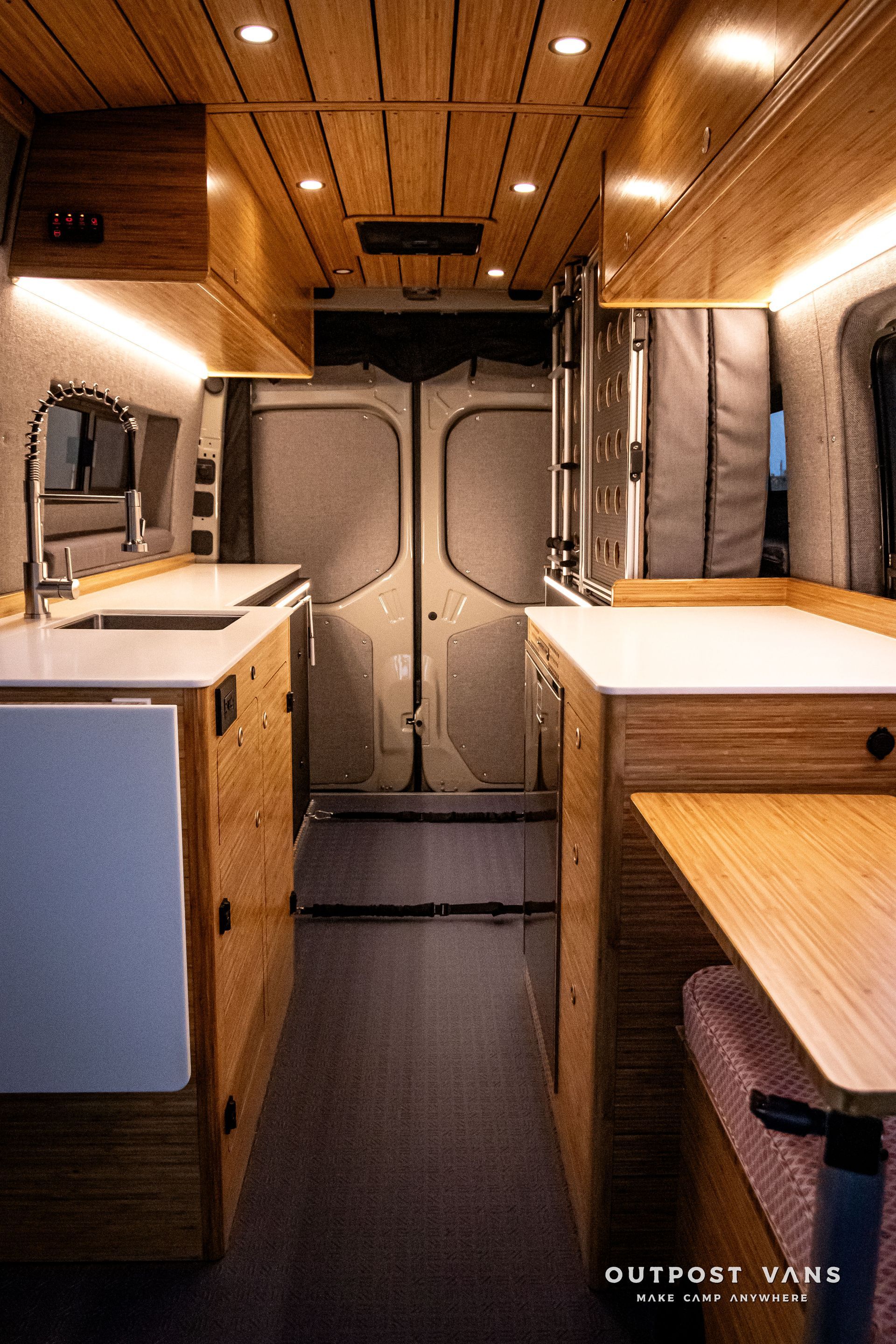 The inside of a camper van with wooden cabinets and a sink.