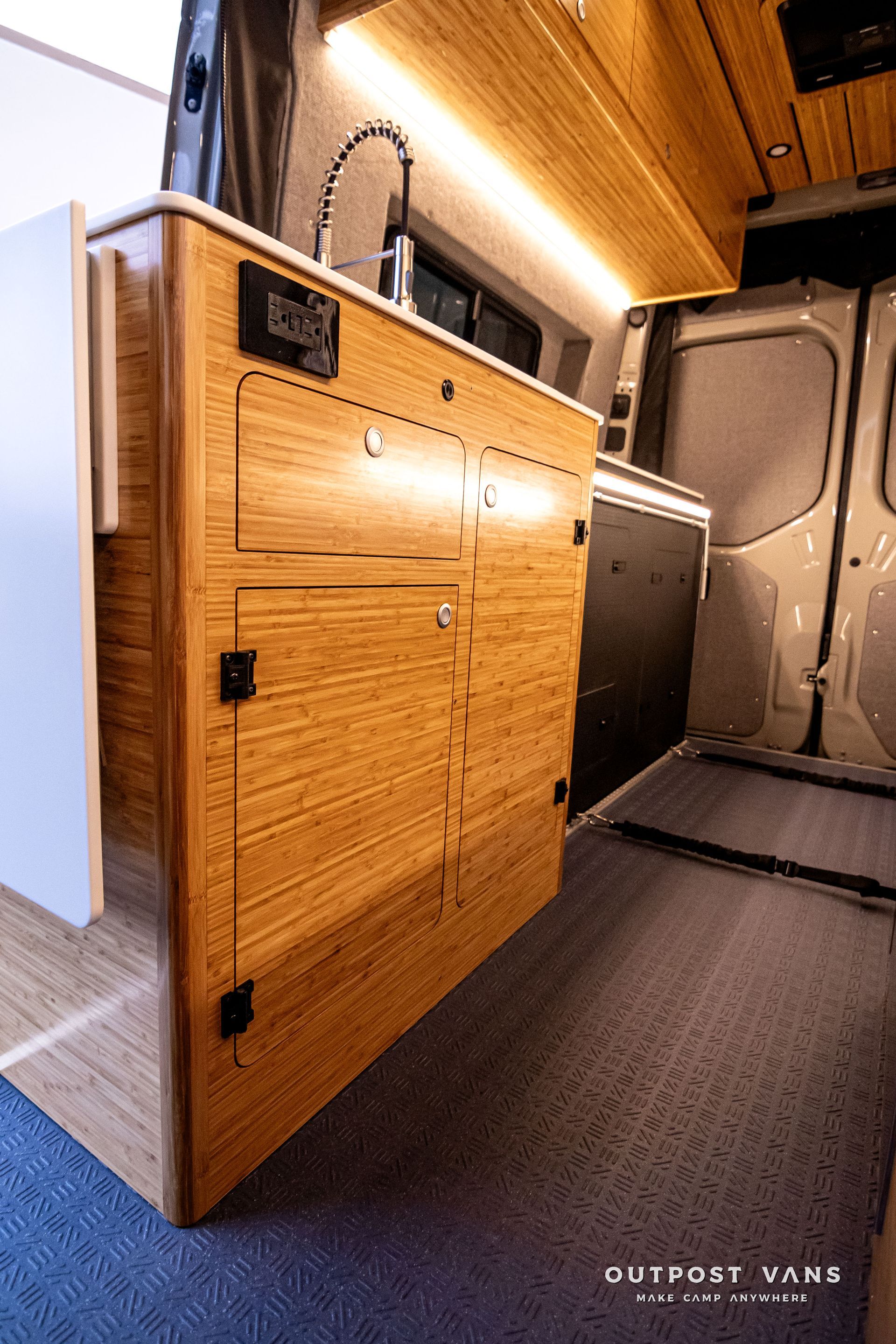 A kitchen in a van with wooden cabinets and a sink.