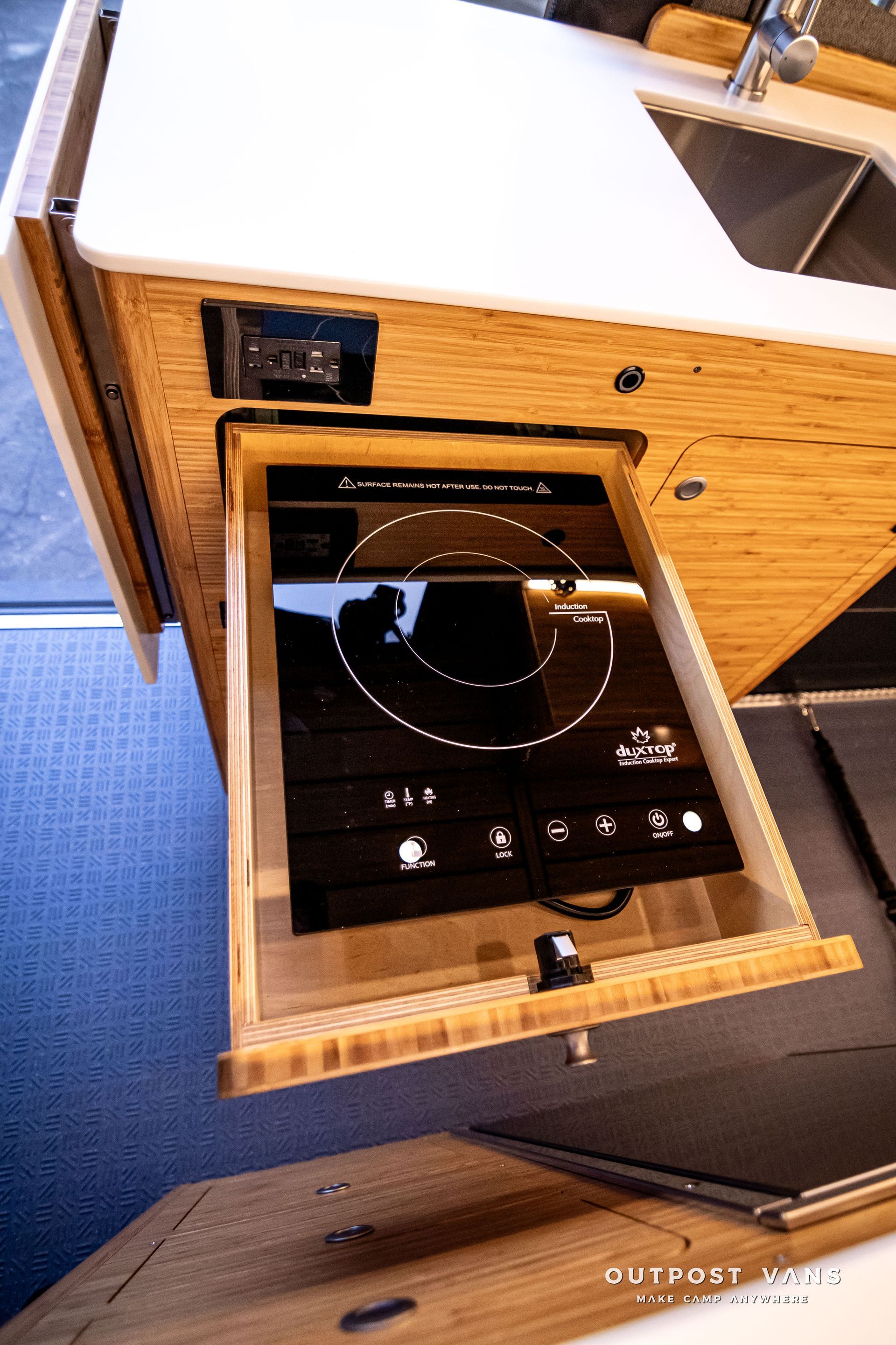 A stove is sitting in a drawer in a kitchen.