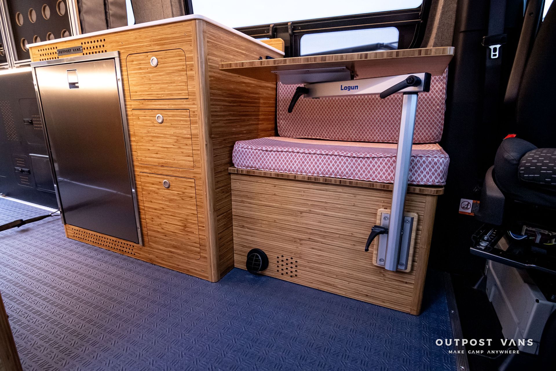 A camper van with a stainless steel refrigerator and wooden cabinets