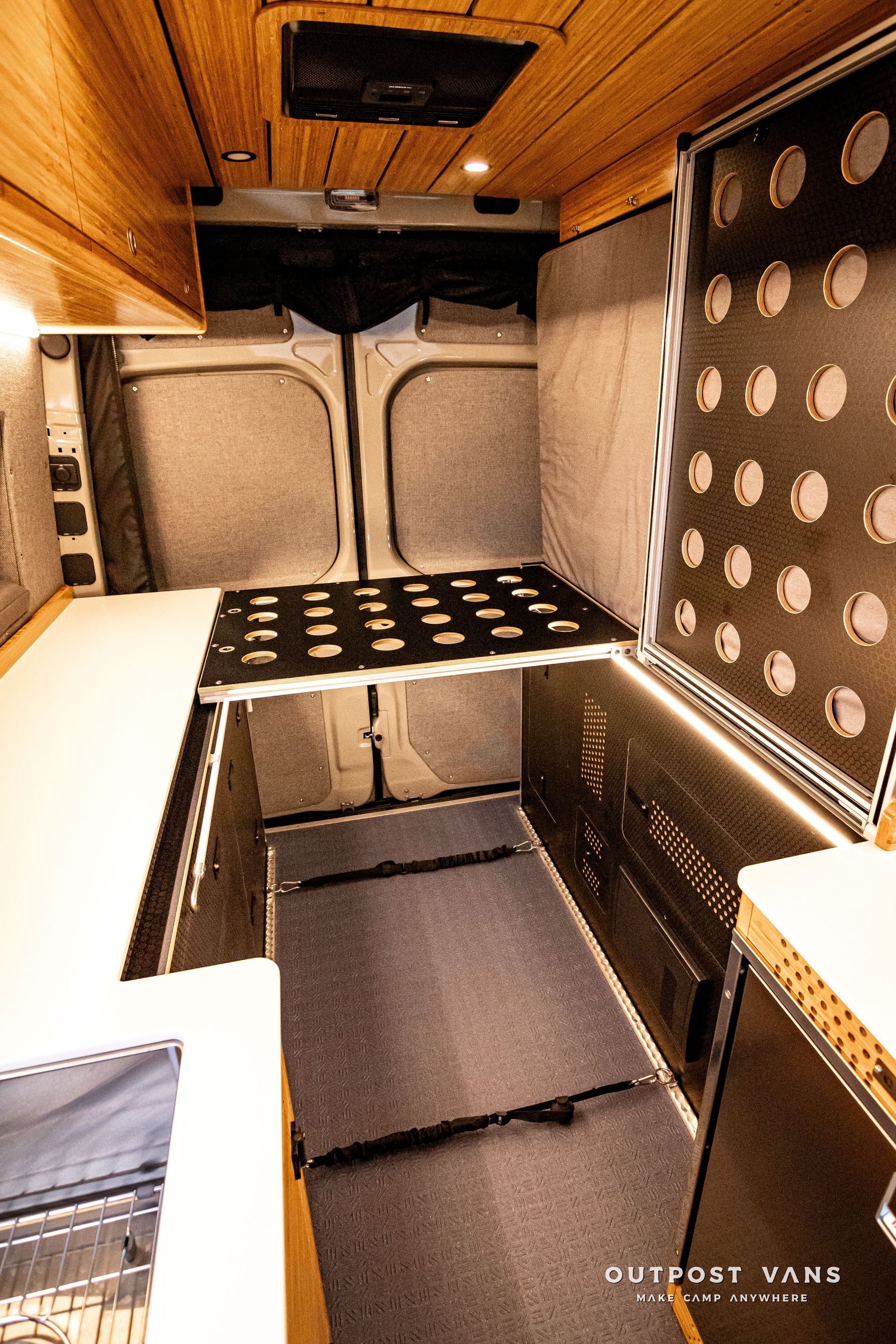 The inside of a van with a bed and a shelf.
