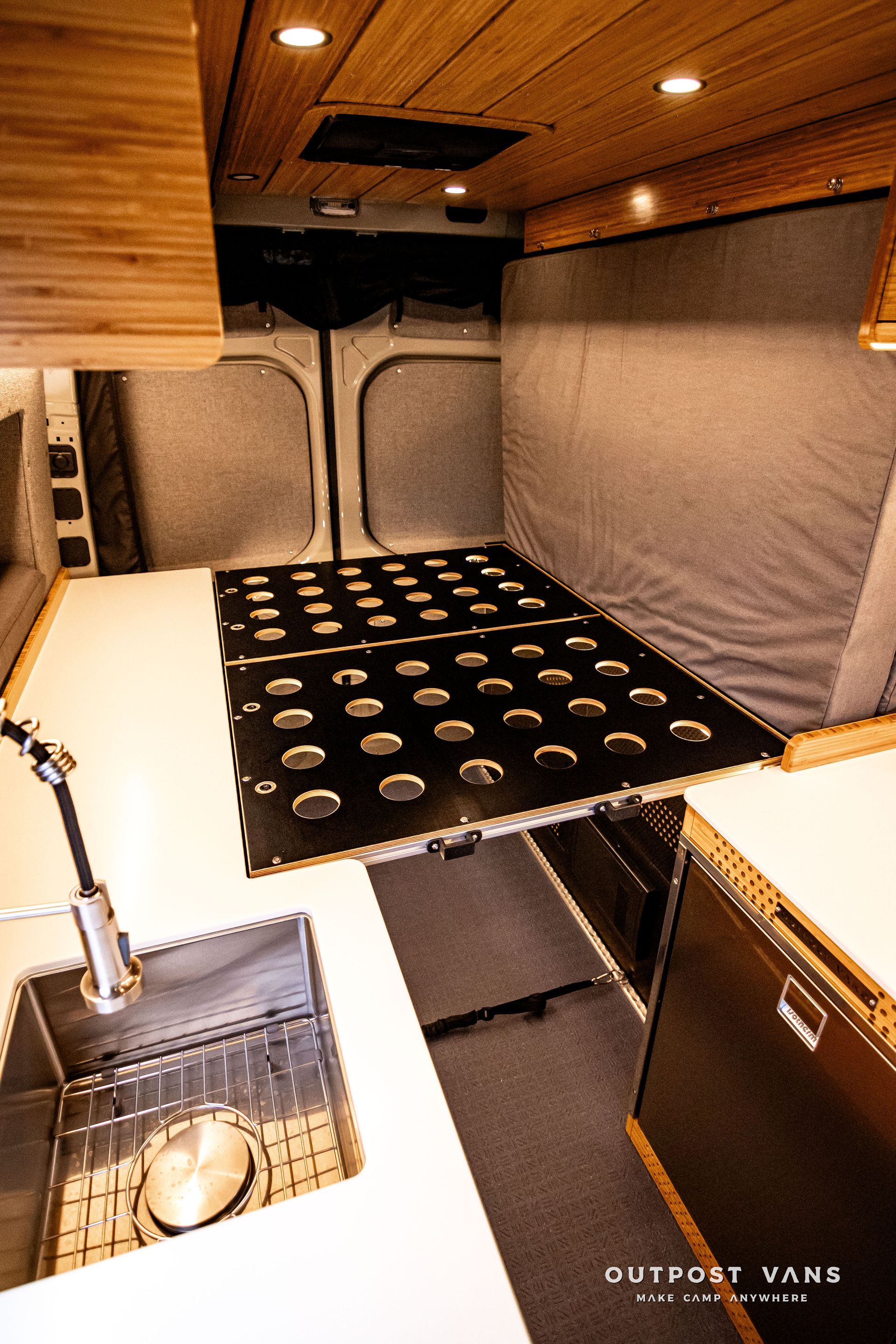 A kitchen with a sink and a bed in the back of a van.