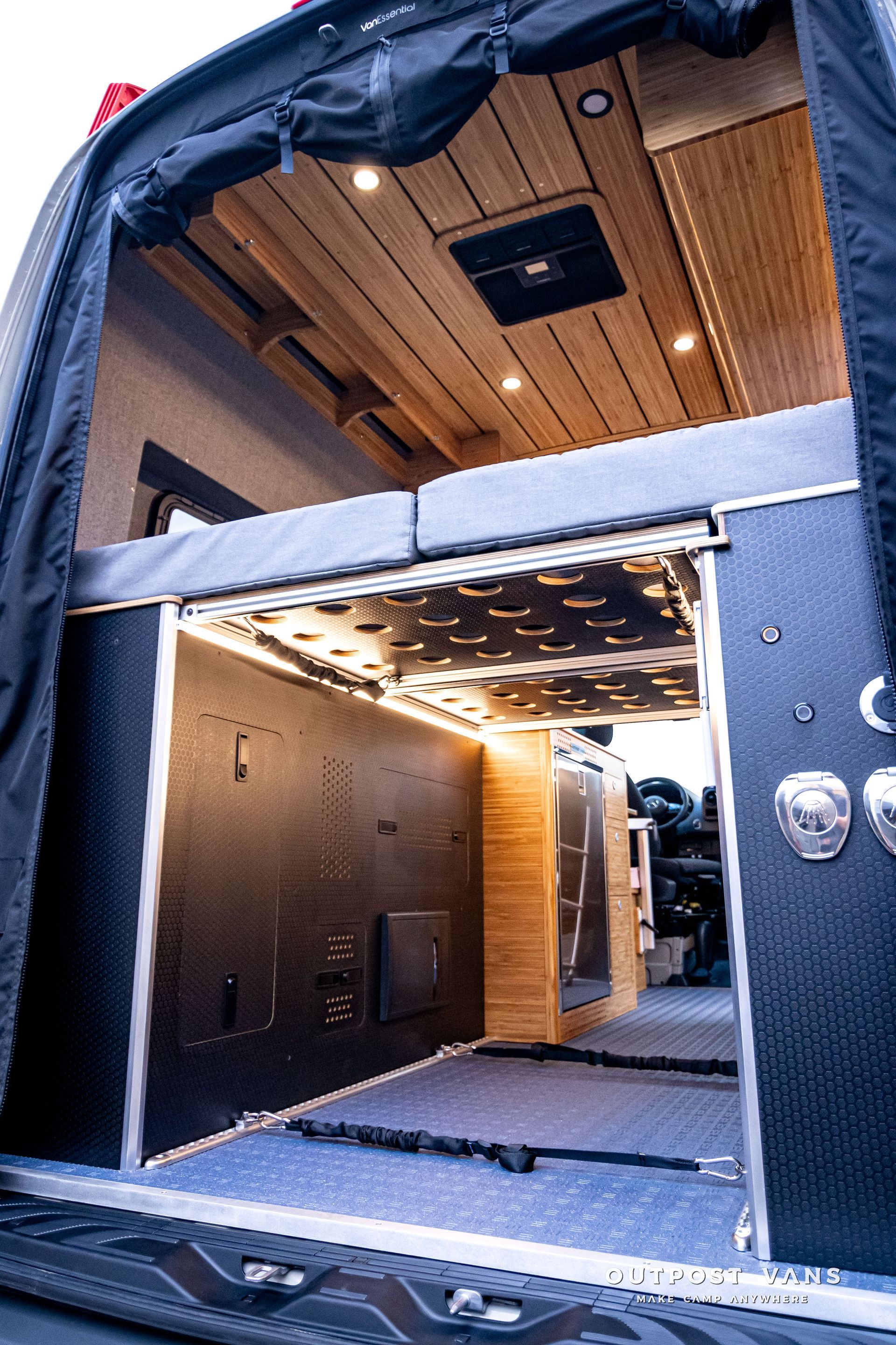 The inside of a van with a bed and a ceiling fan.