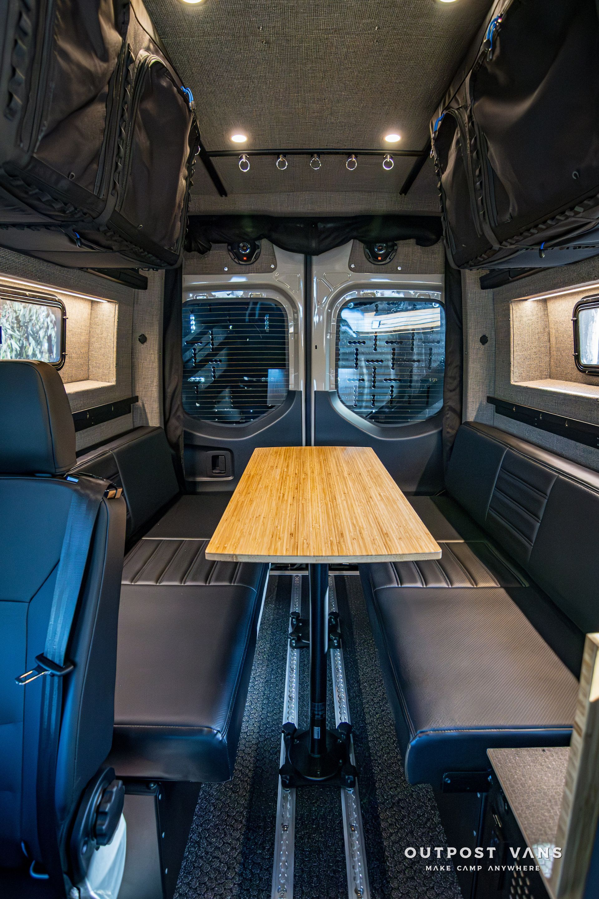 The inside of a van with a table and benches.