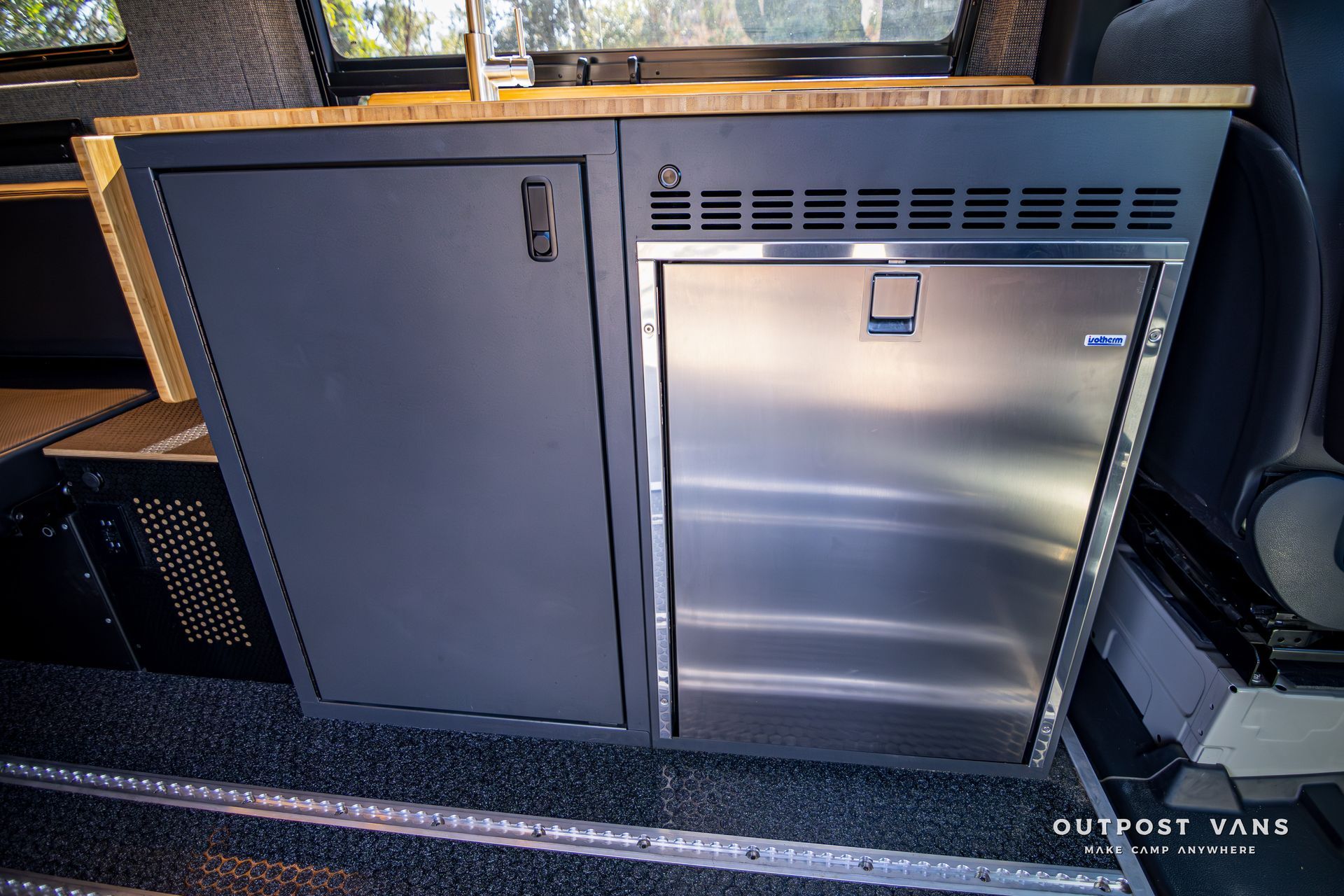 A kitchen in a van with a stainless steel refrigerator.