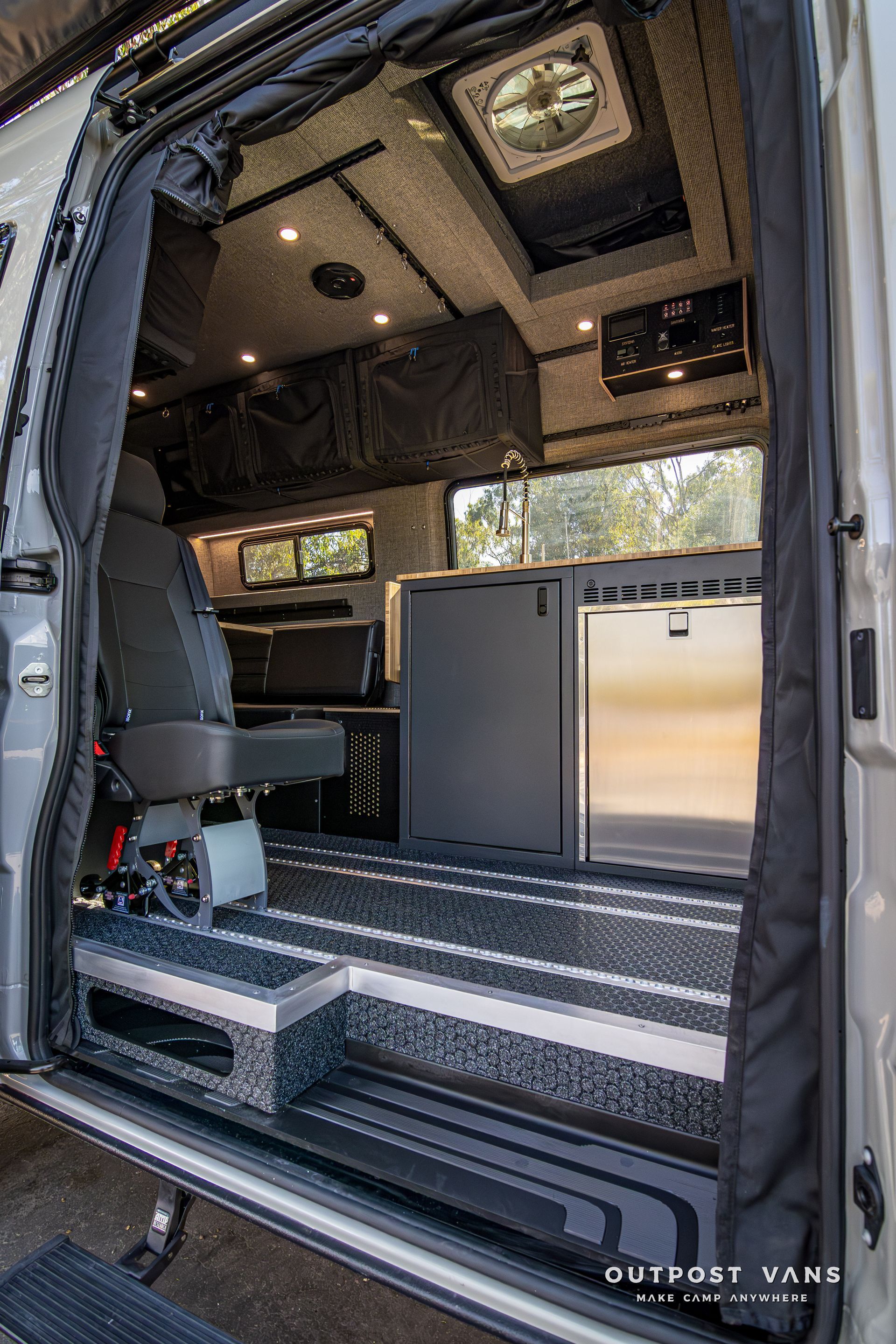 The inside of a van with the door open and a fan on the ceiling.