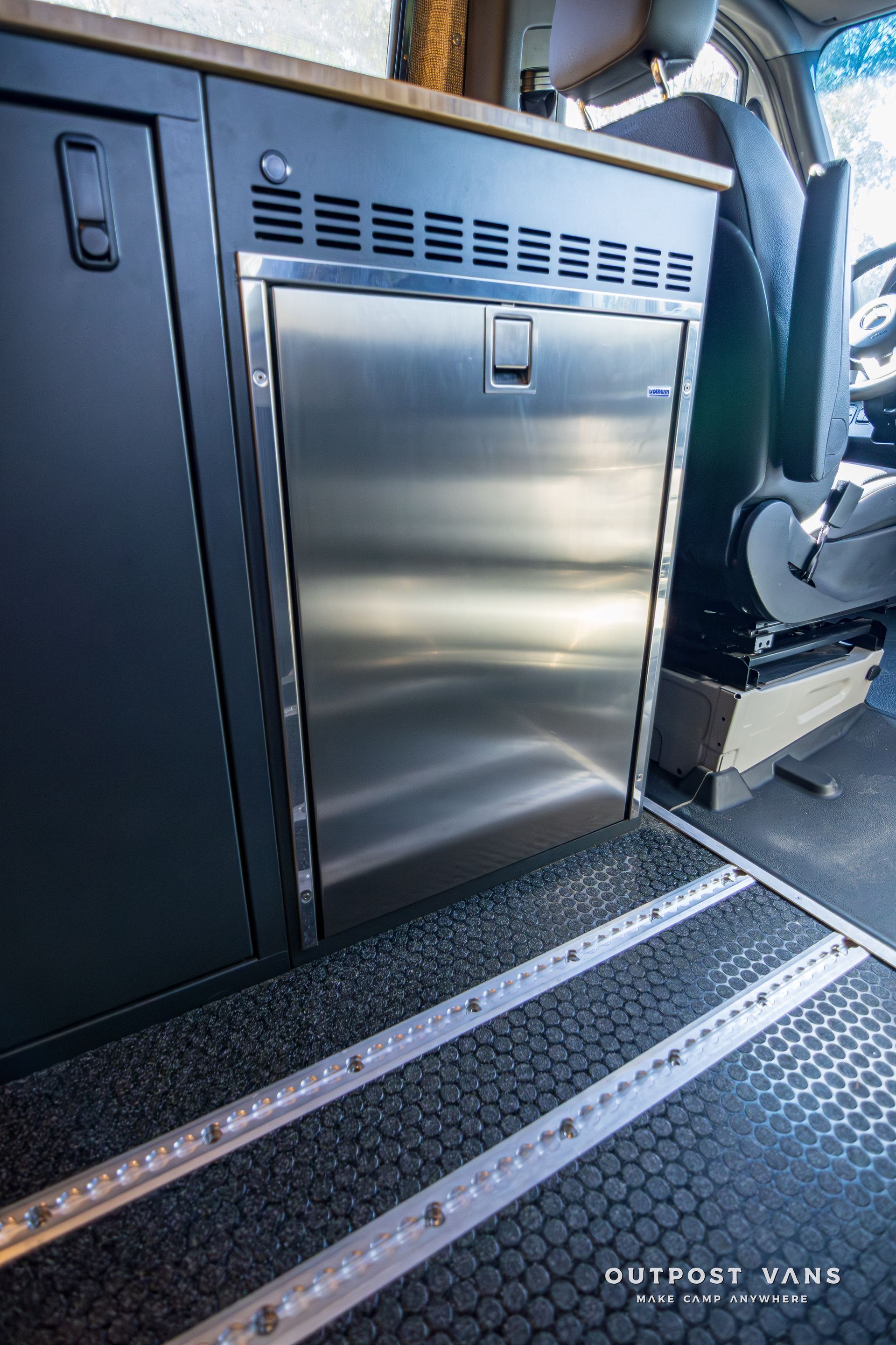A stainless steel refrigerator is in the back of a van.