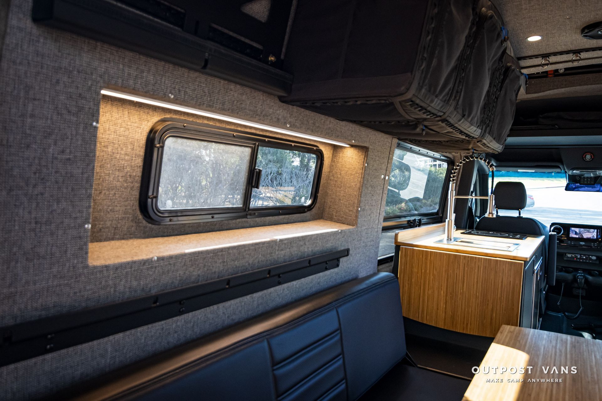 The inside of a van with a couch , table , and window.