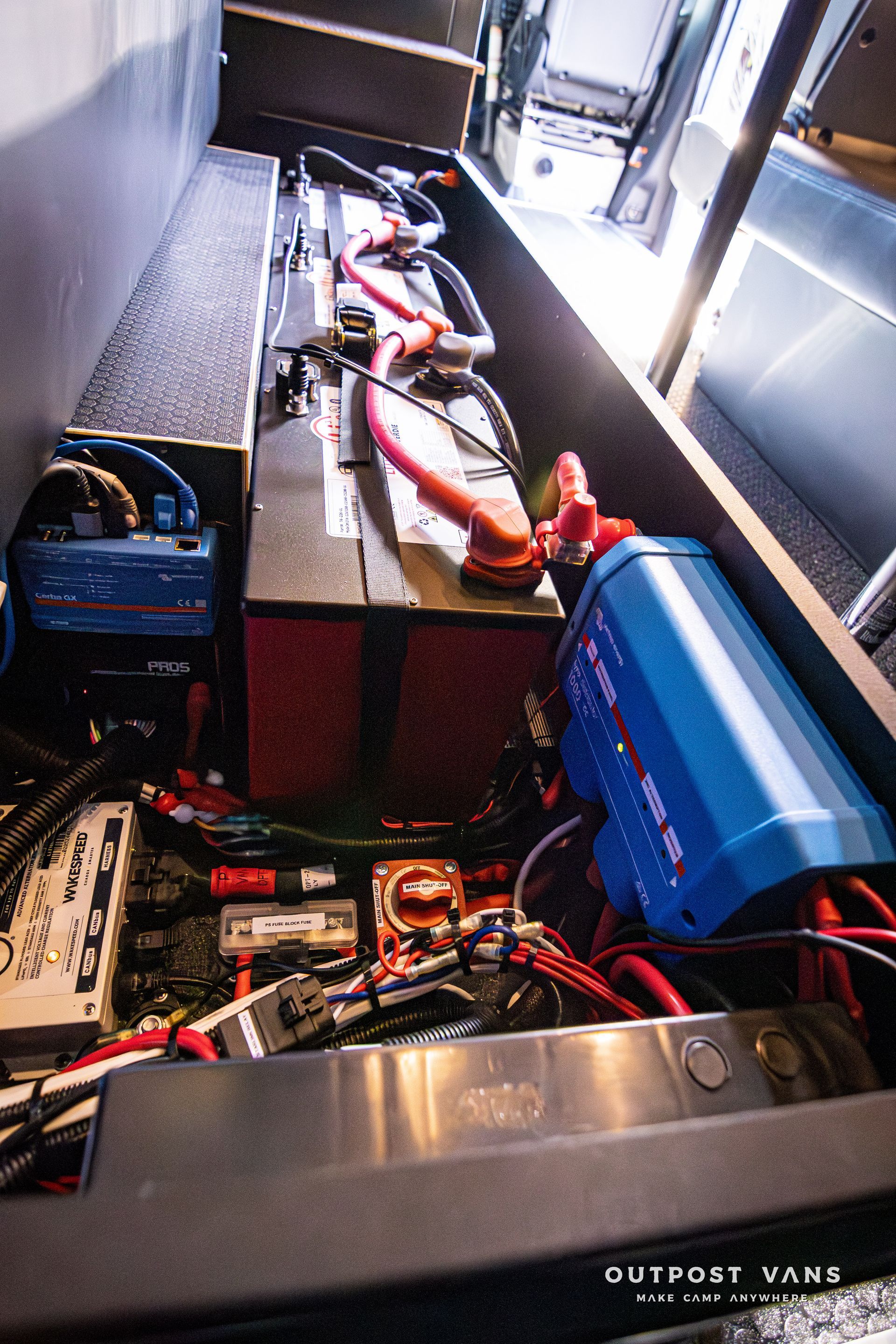 The inside of a van with a lot of wires and batteries