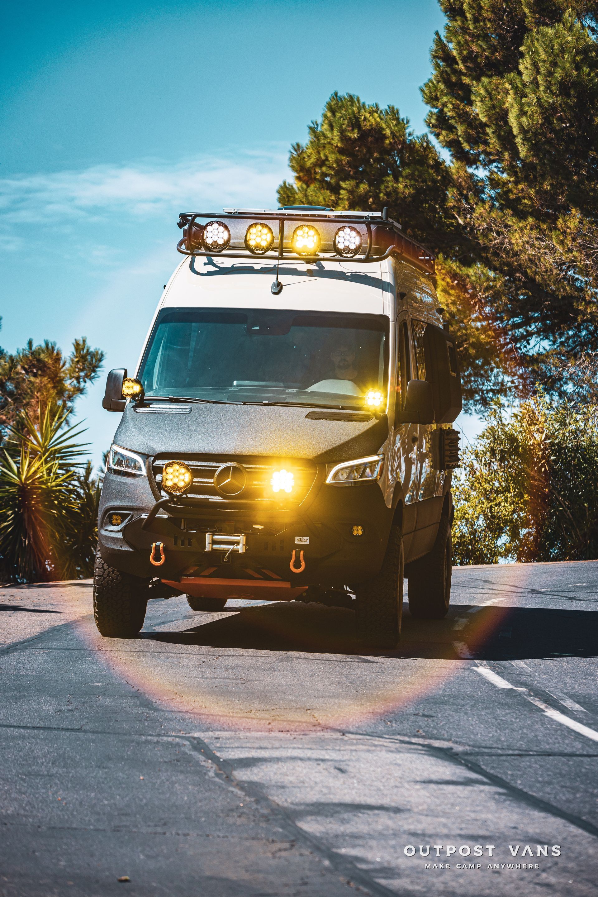 An ambulance is driving down a road with trees in the background.