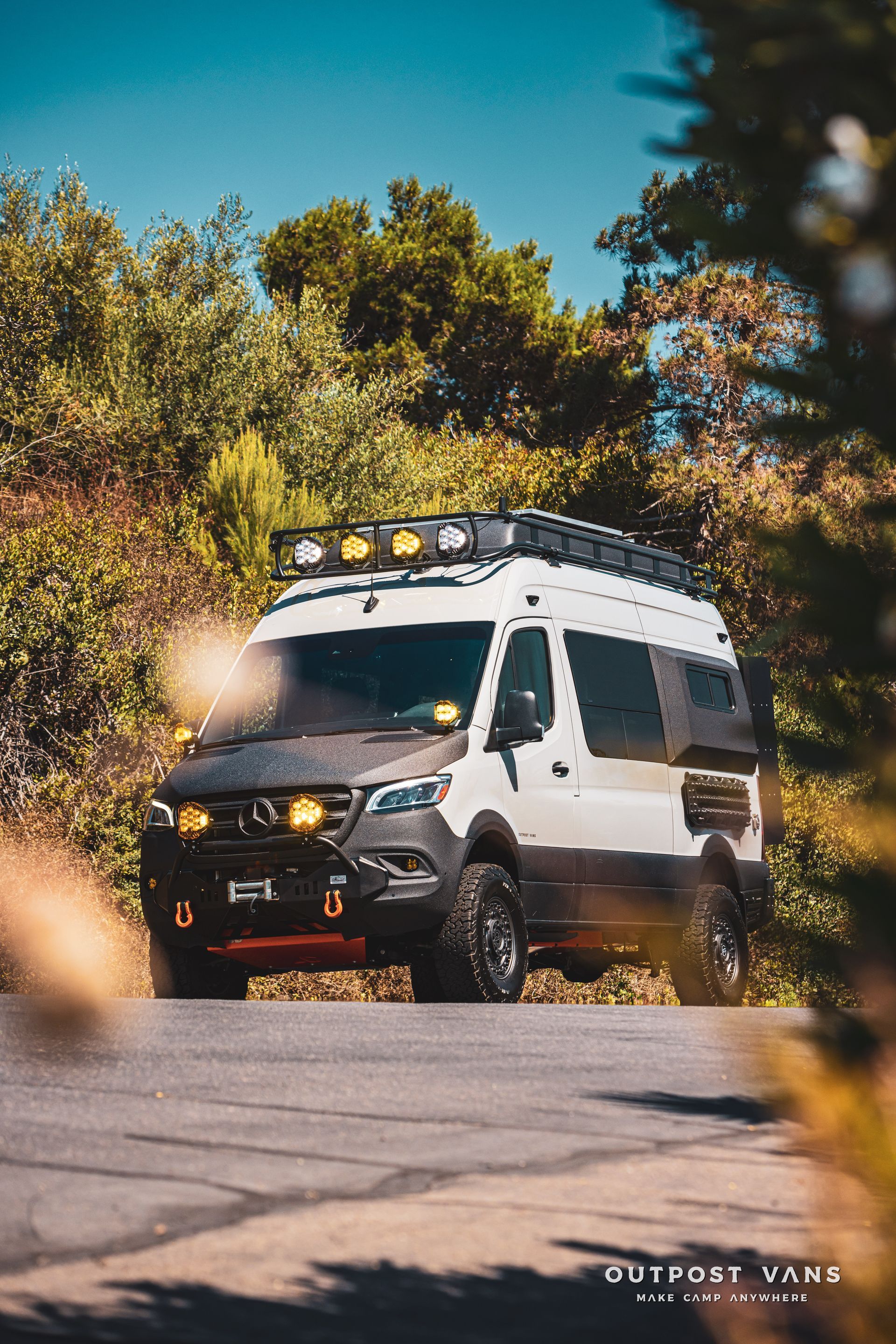 A white van with a roof rack is driving down a road.