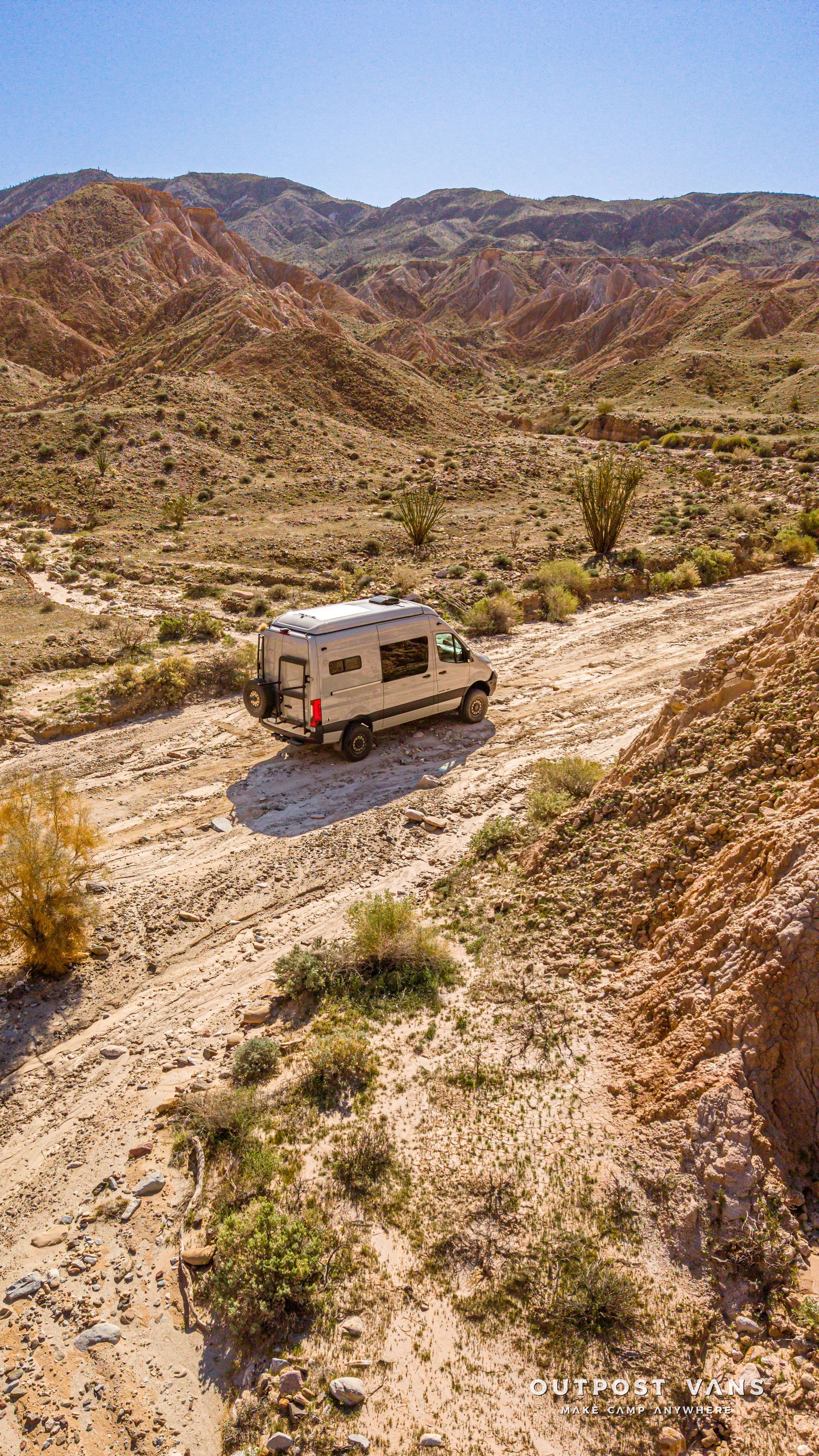 RV on a dirt road in a rocky desert canyon landscape