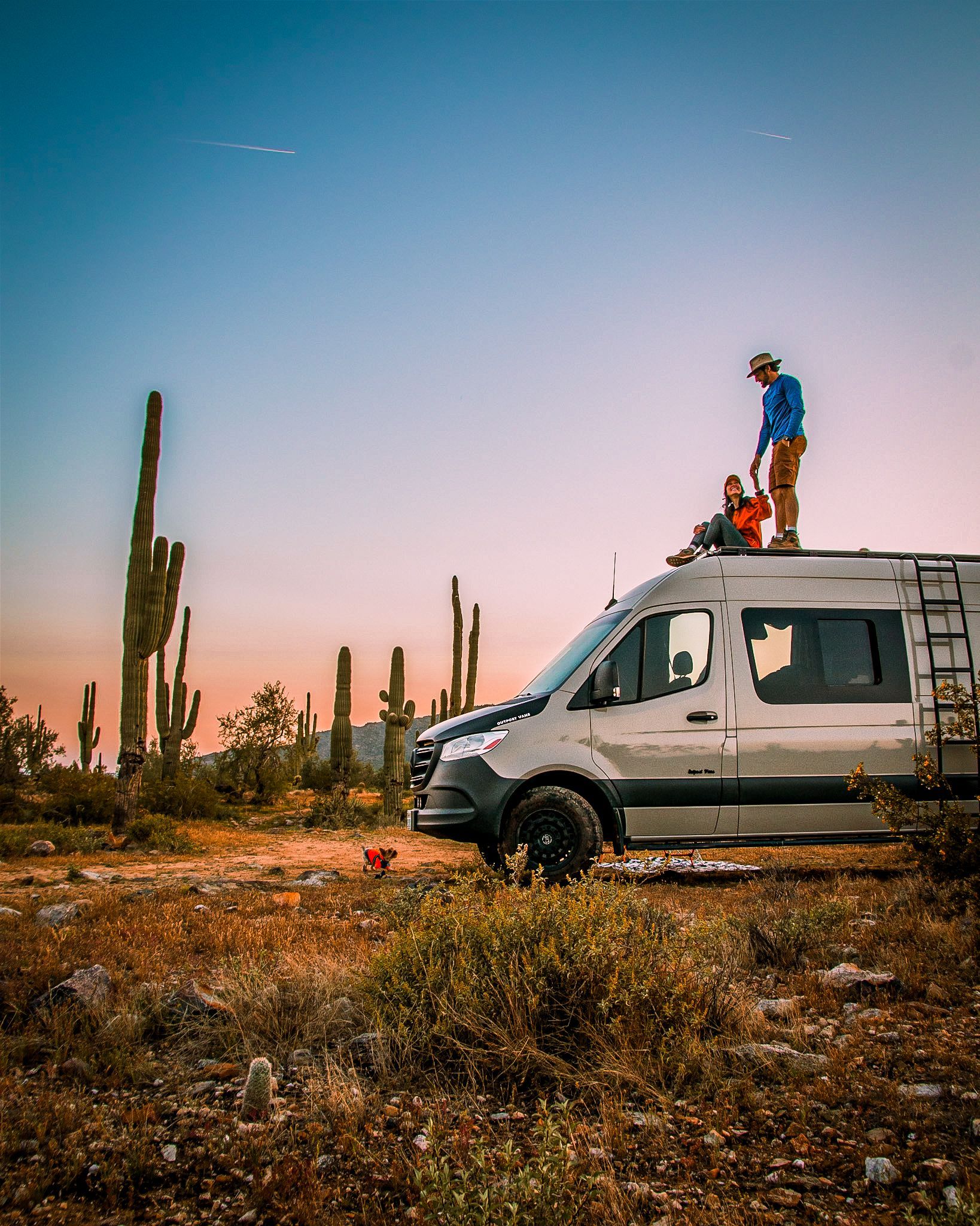 a man is standing on top of a van in the desert .