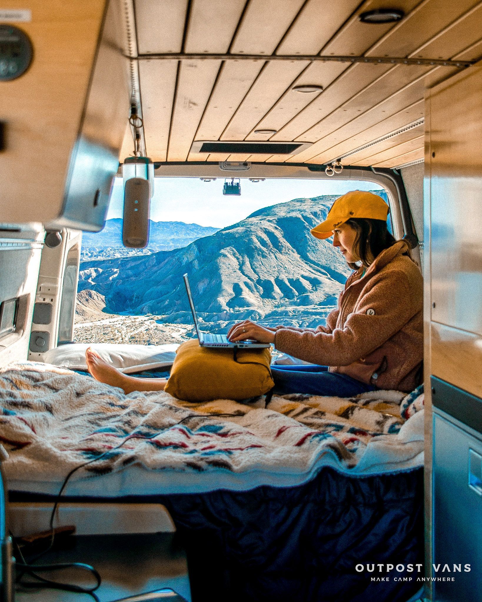 a woman is sitting in the back of a van using a laptop .