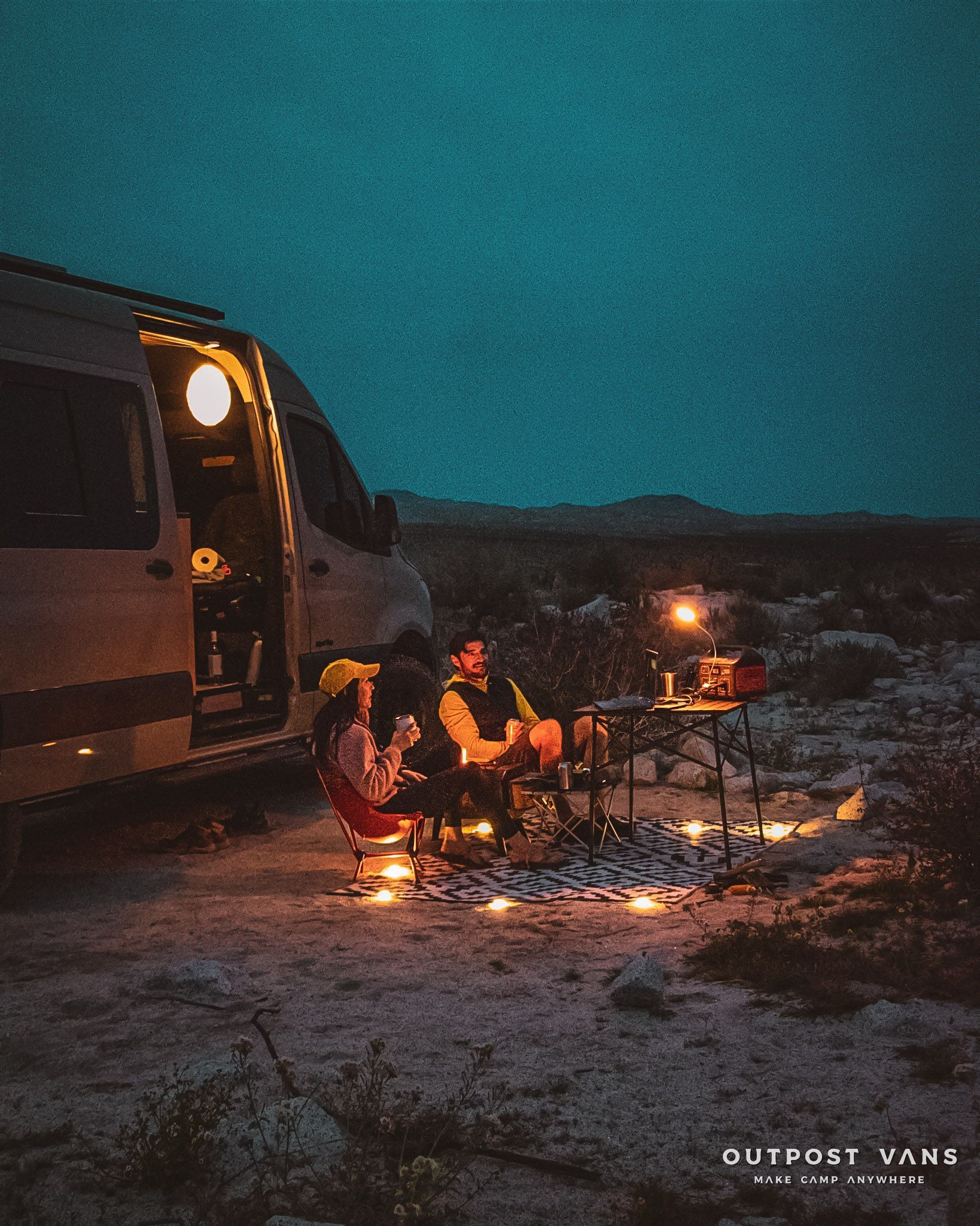a group of people are sitting outside of a van at night .