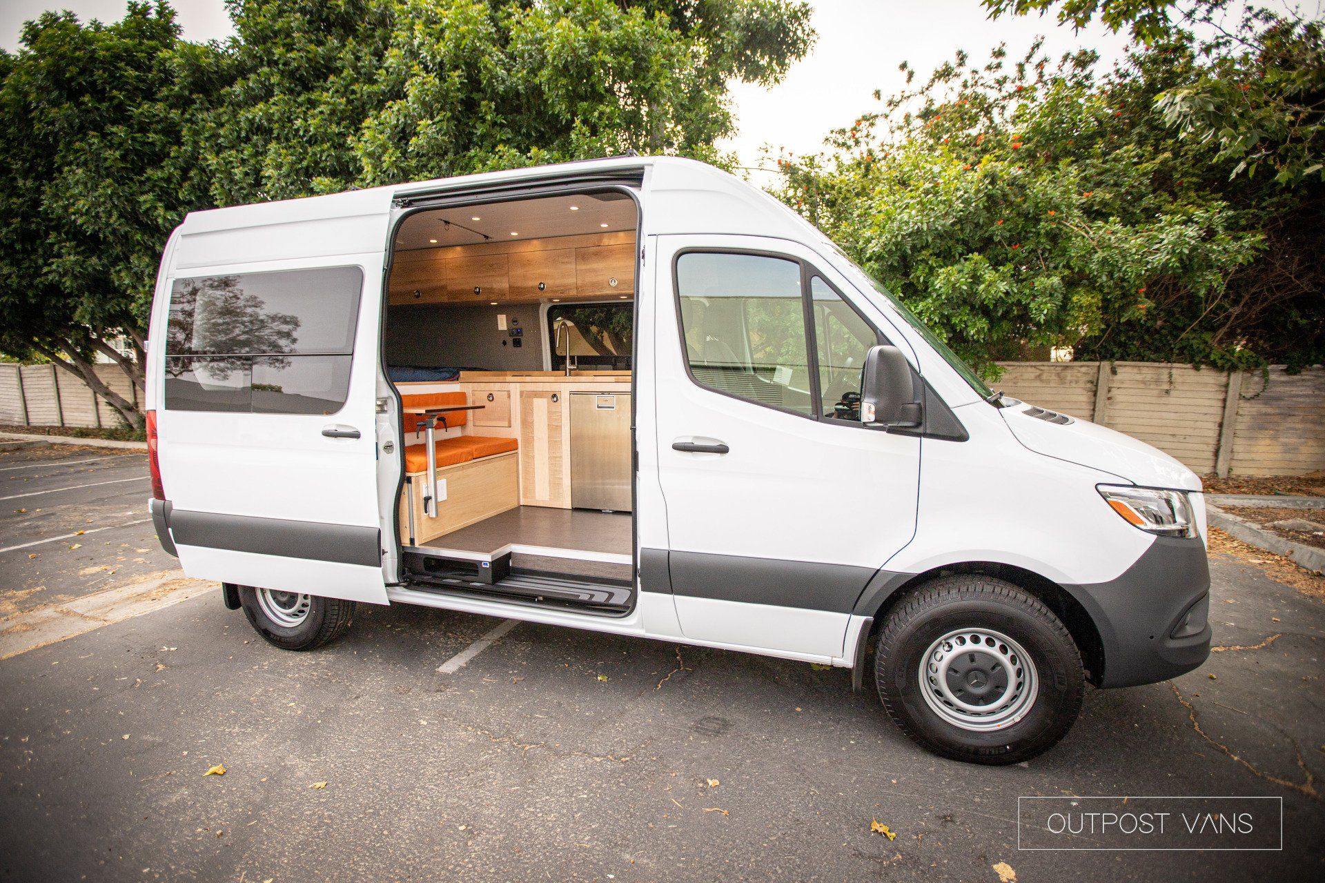A white van is parked in a parking lot with its doors open.