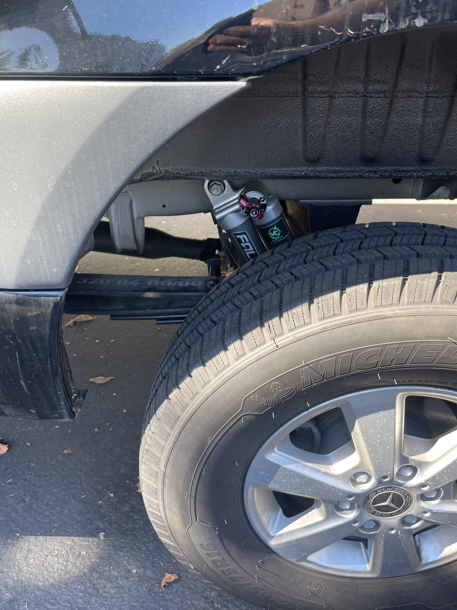 A close up of a tire on a truck with a shock on it.