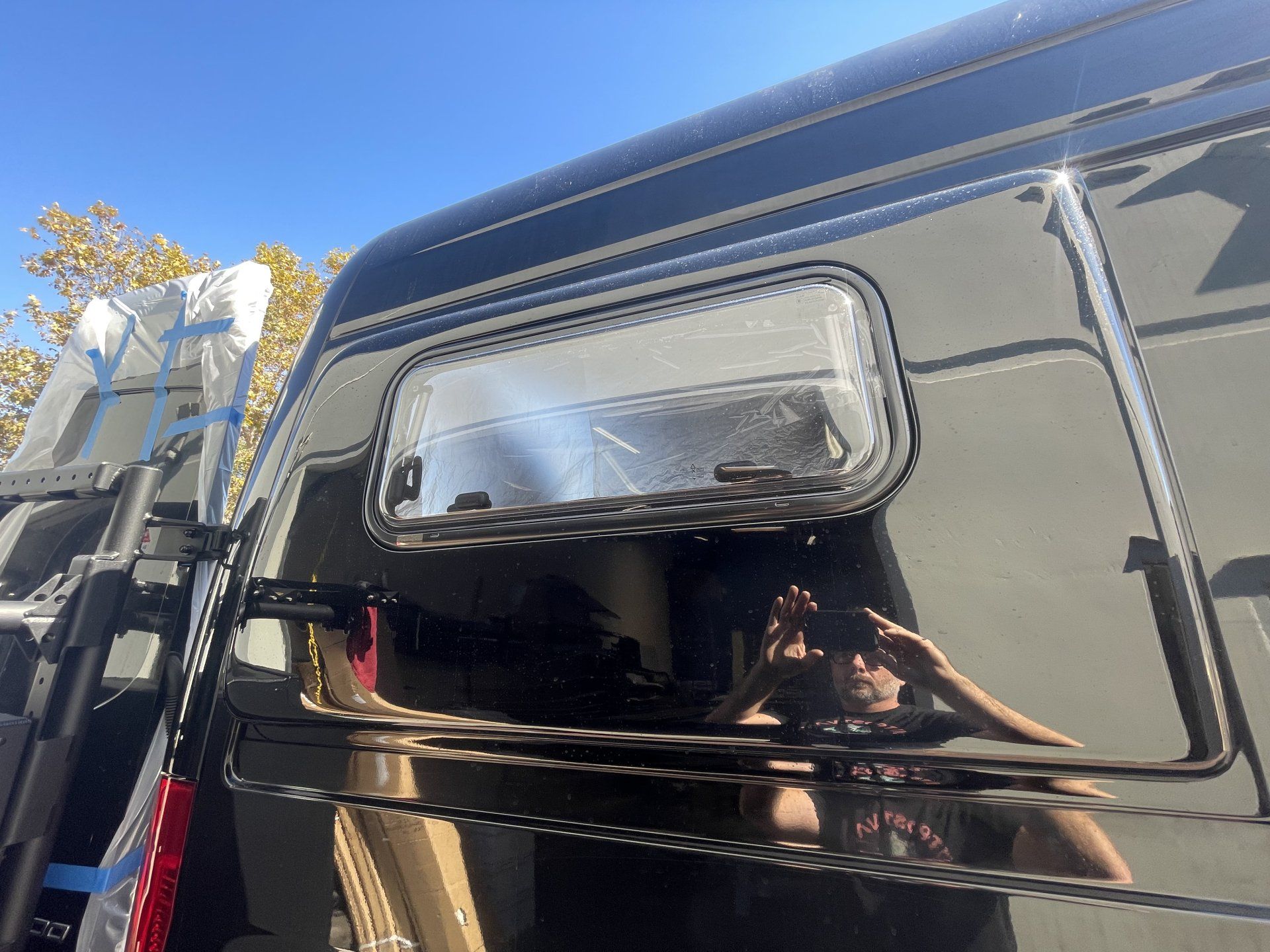 A man is taking a picture of himself in the window of a van.