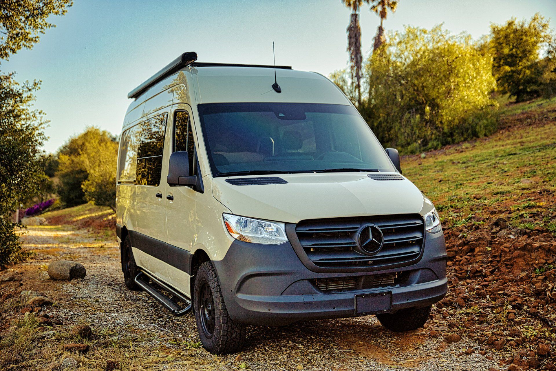 A white van is parked on the side of a dirt road.