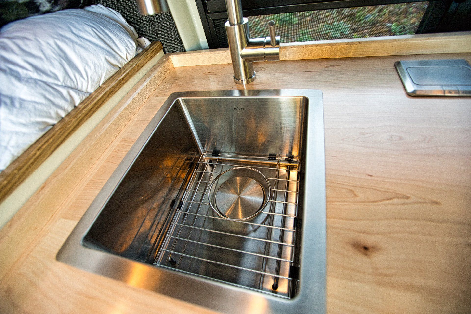 A stainless steel sink is sitting on a wooden counter.