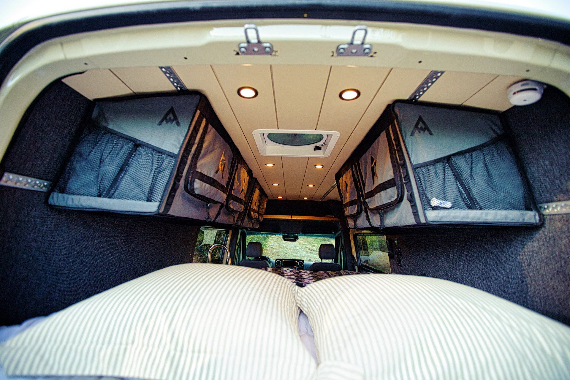 The back of a van with a bed and lots of storage space