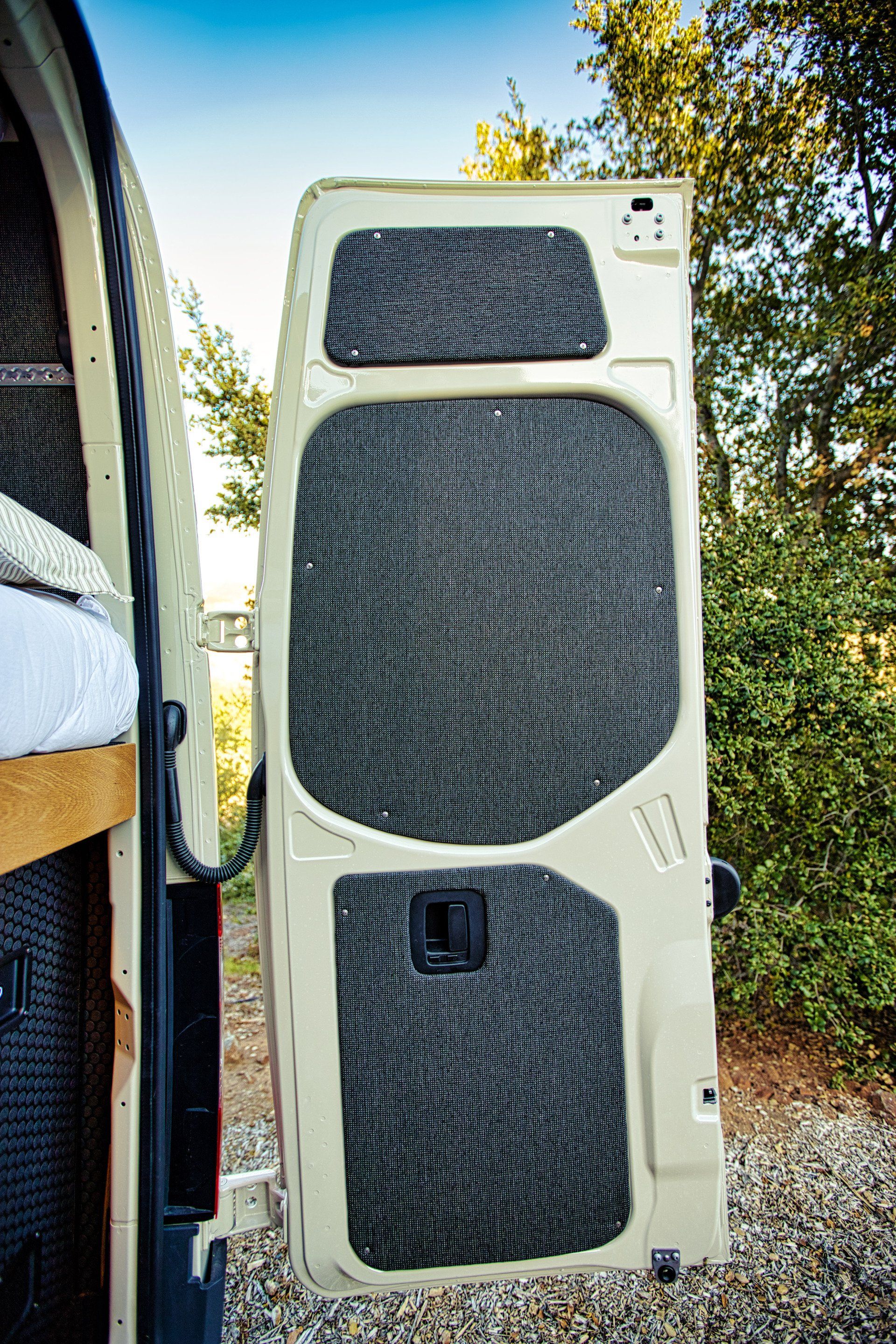 A white van with the door open and a bed in the back.