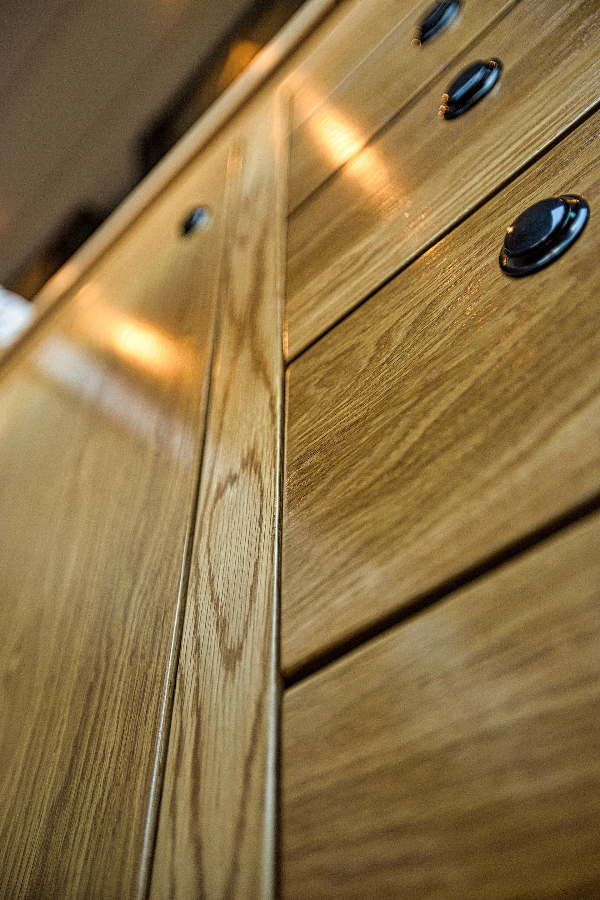 A close up of a wooden cabinet with drawers and black handles.