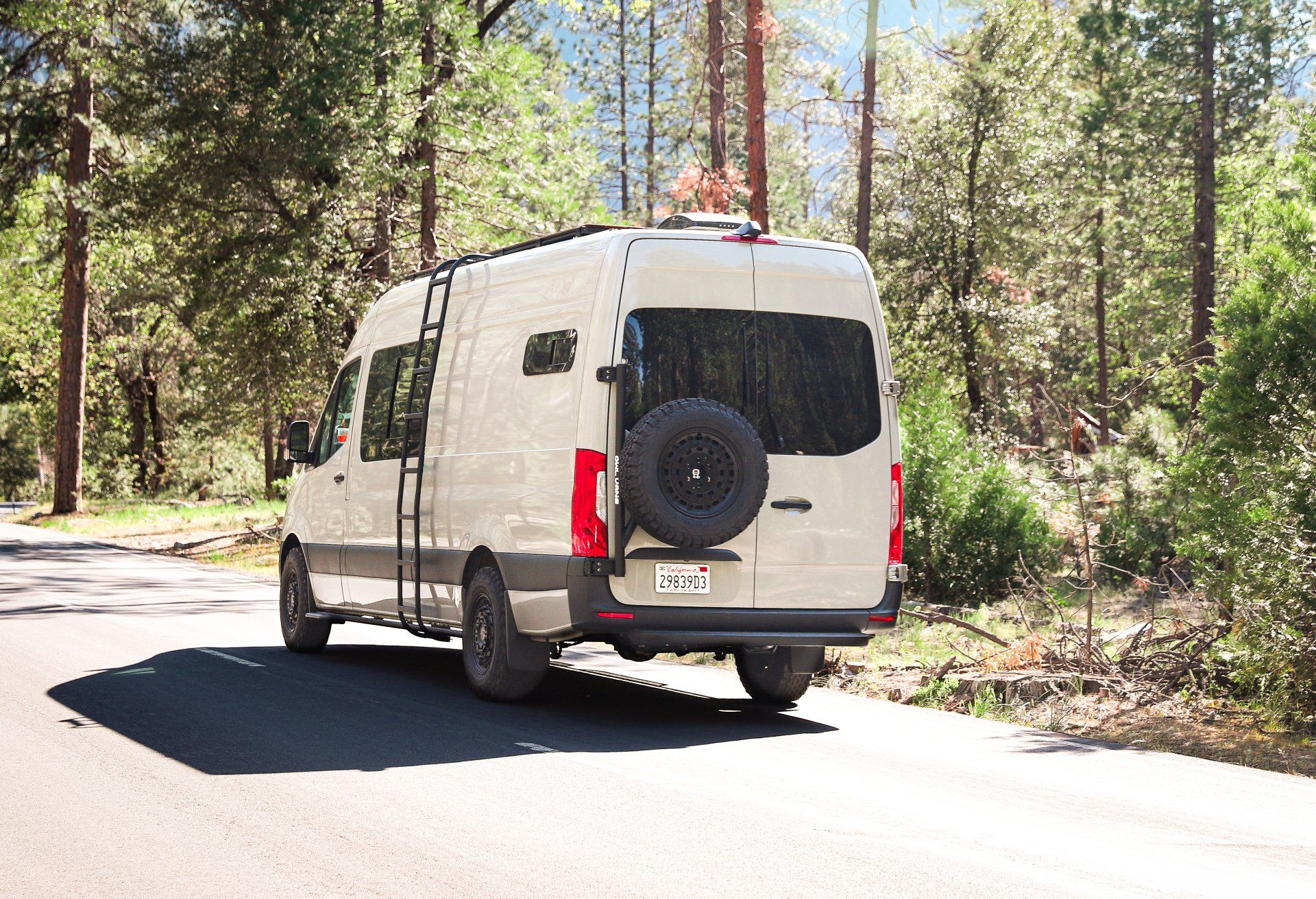 a white van is driving down a road in the woods .