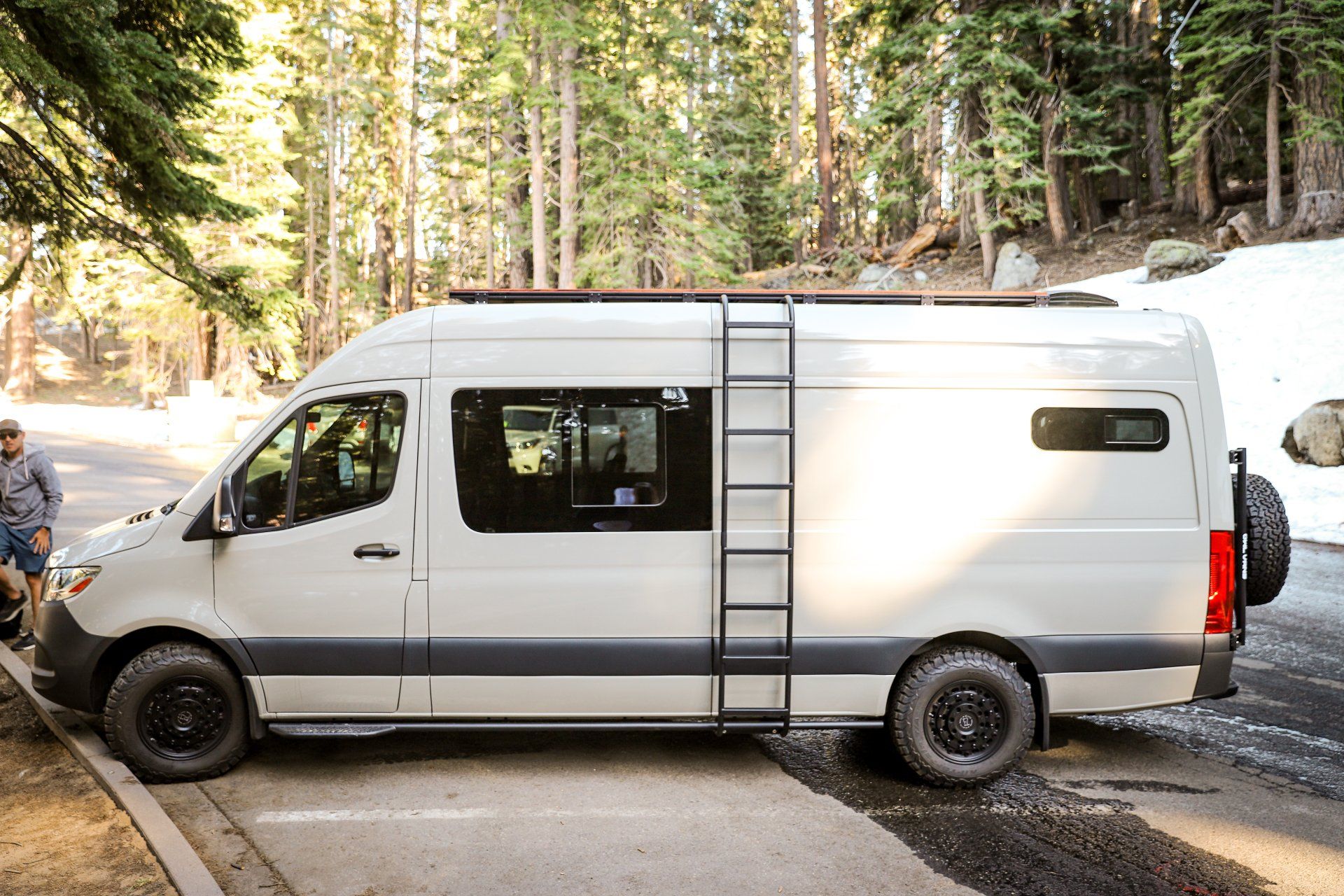 a white van with a ladder on the roof is parked on the side of the road .