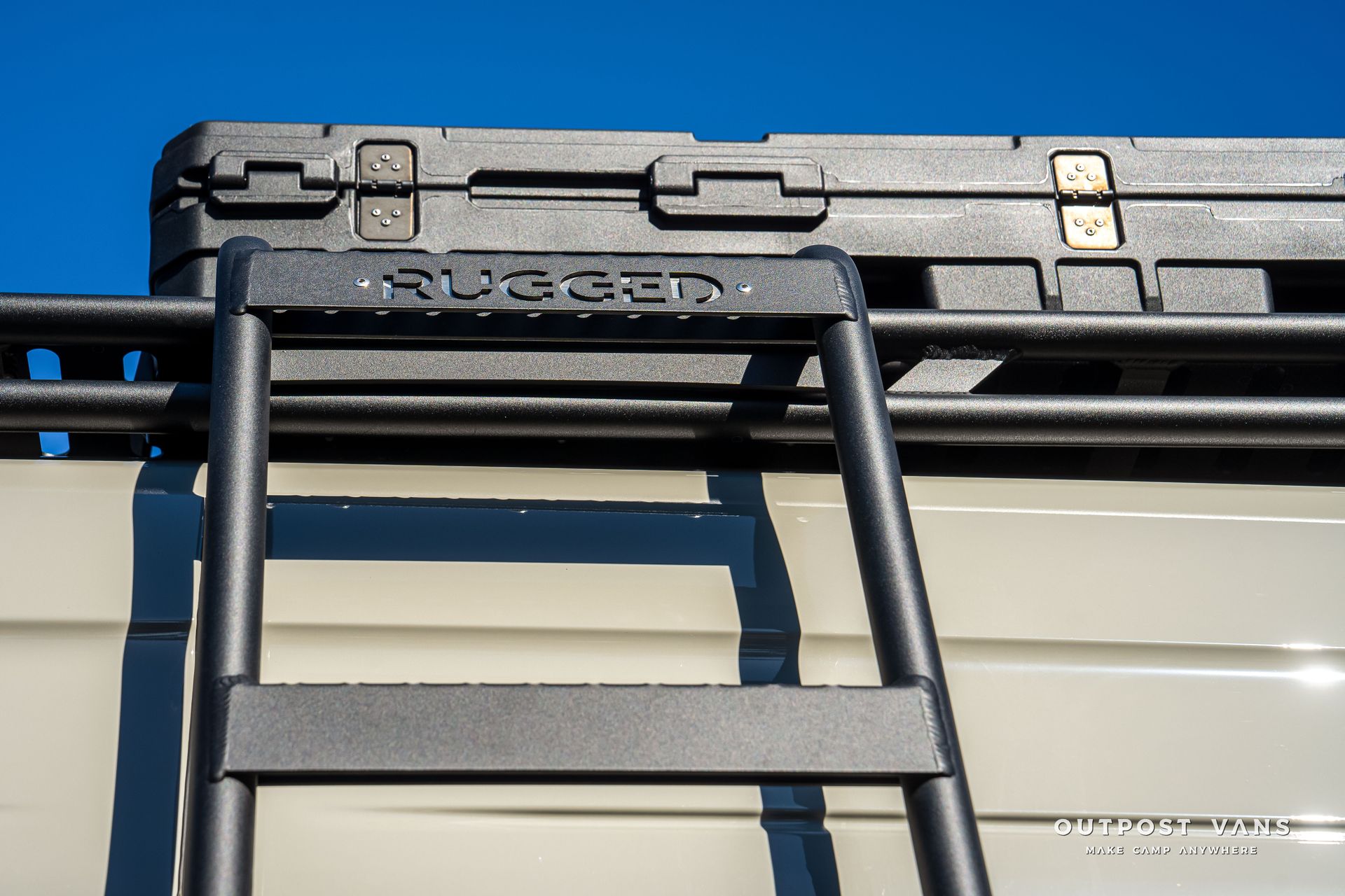 Black ladder attached to a vehicle roof rack with a