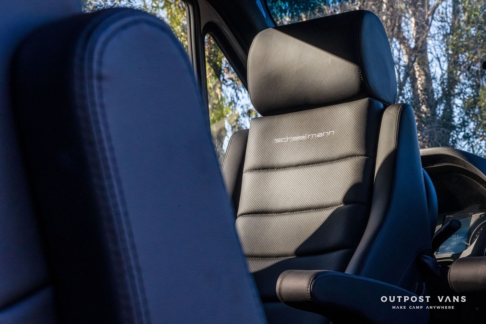 Close-up of a vehicle's black interior seat. The seat has a textured center and a leather-like armrest.