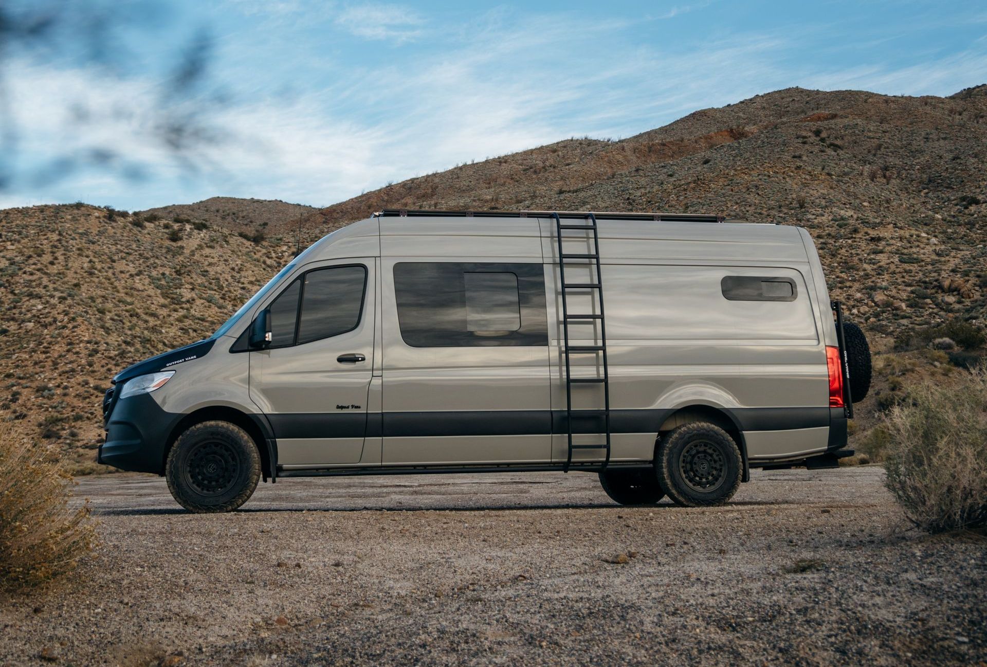 a van with a ladder attached to the side is parked on a dirt road .