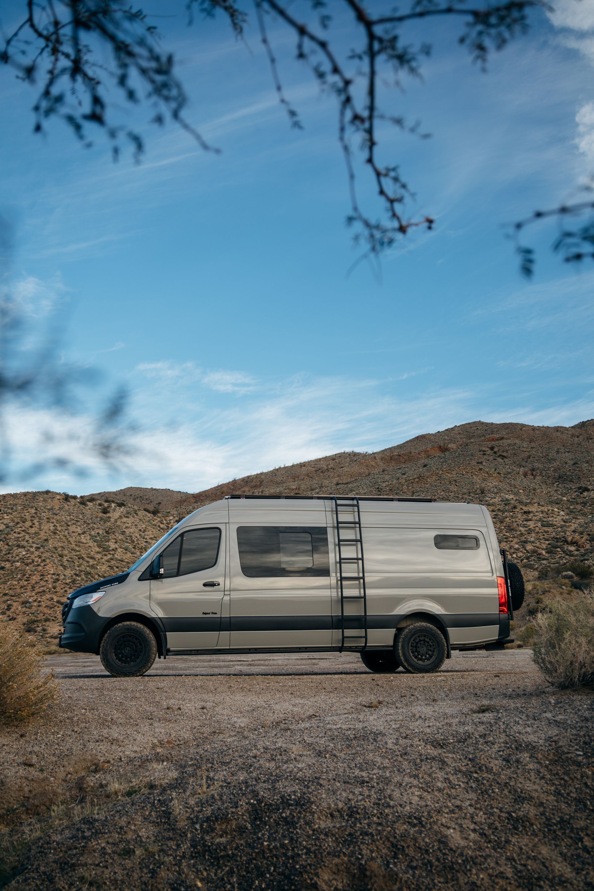 a van is parked on the side of a dirt road in the desert .