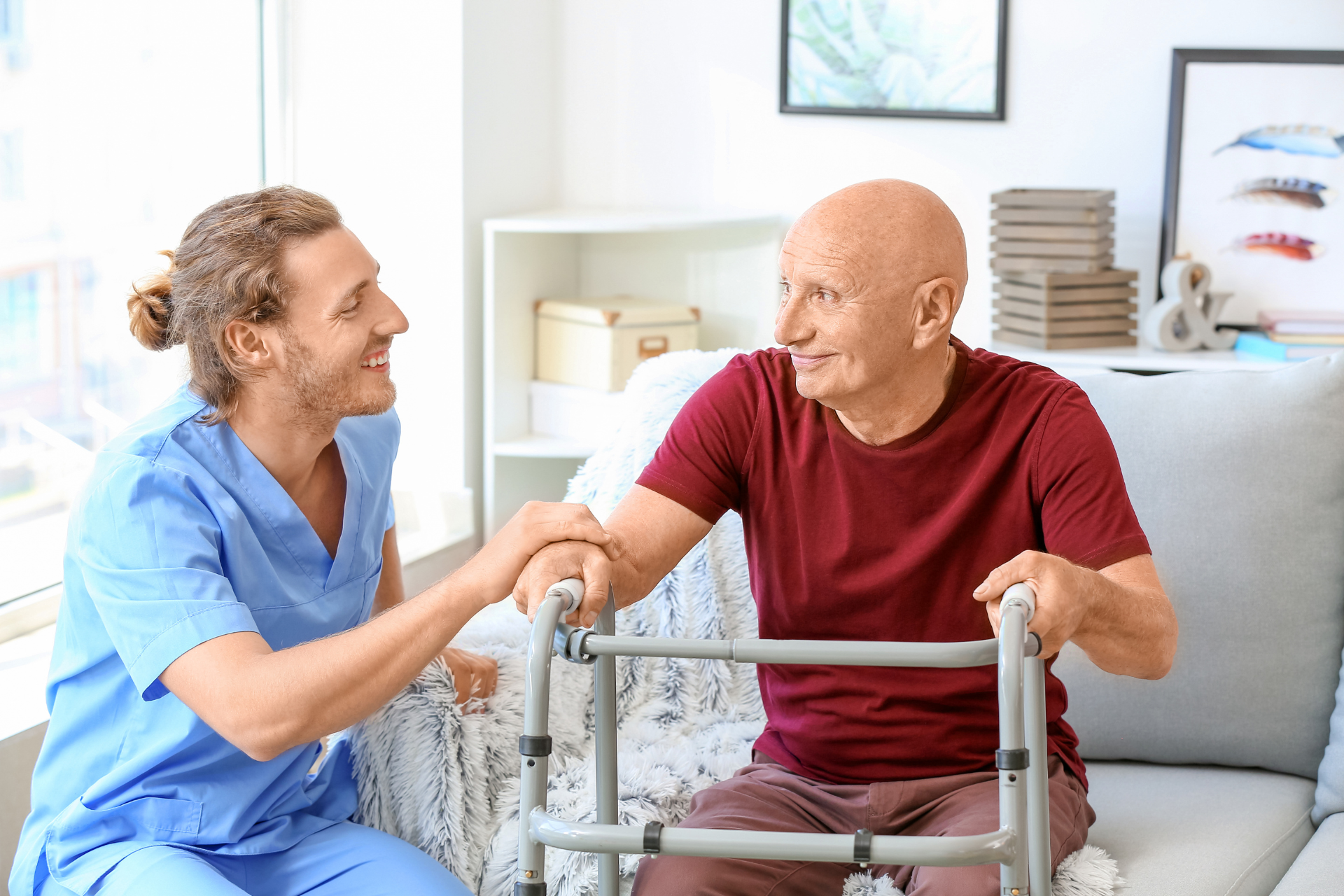Caregiver helping a patient use a walker in a bright home living room