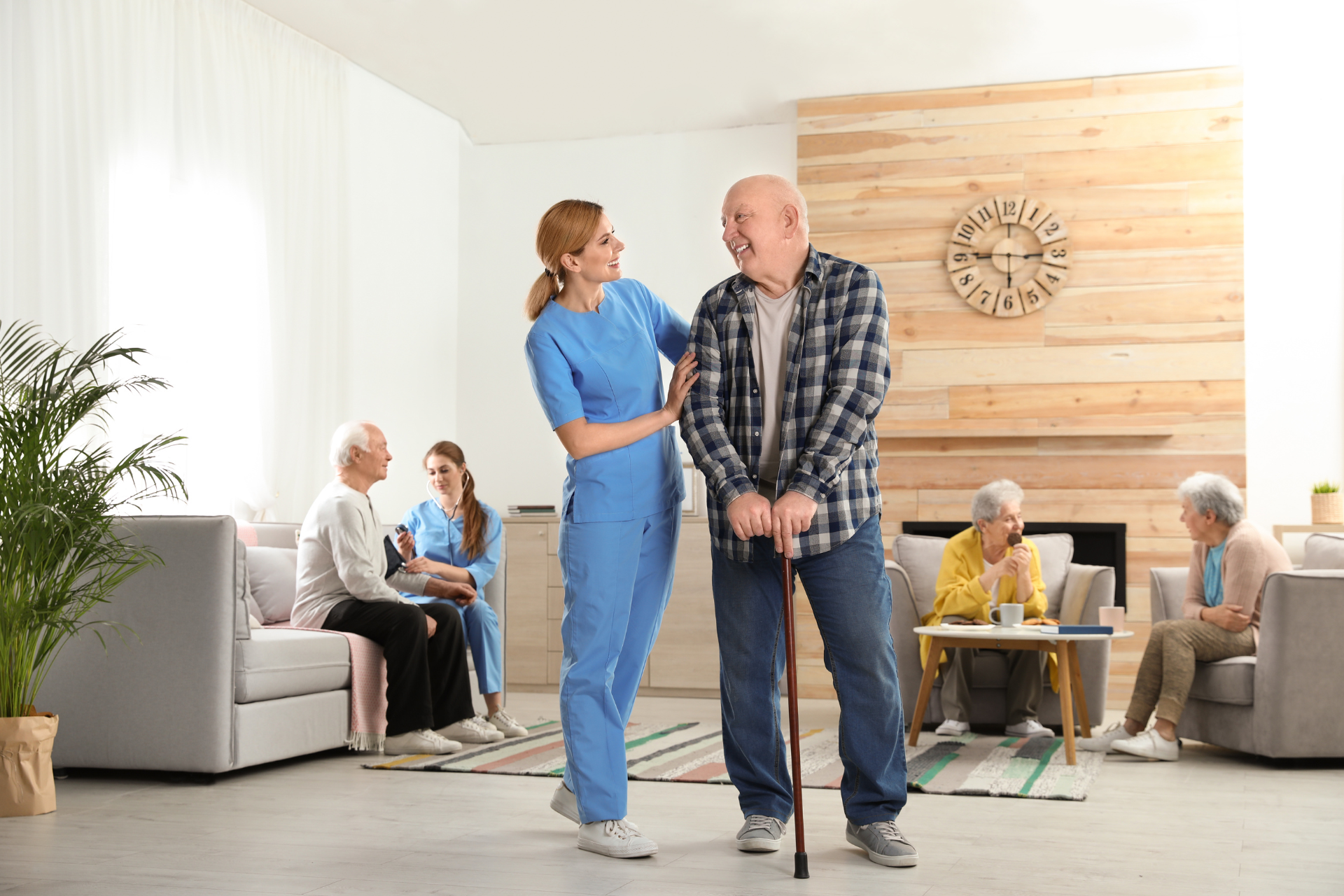 Caregiver helping a man with a cane in a bright senior living lounge