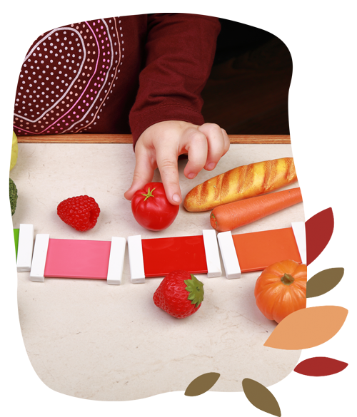 A child explores strawberries and carrots, following the Montessori philosophy of hands-on learning.