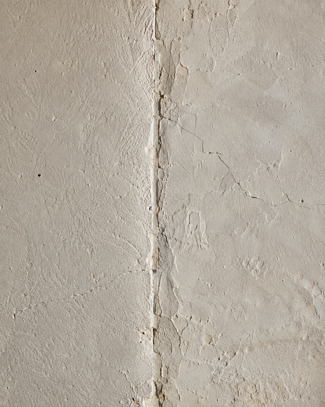 Close-up detail of aged plaster wall material showing surface texture and seams.