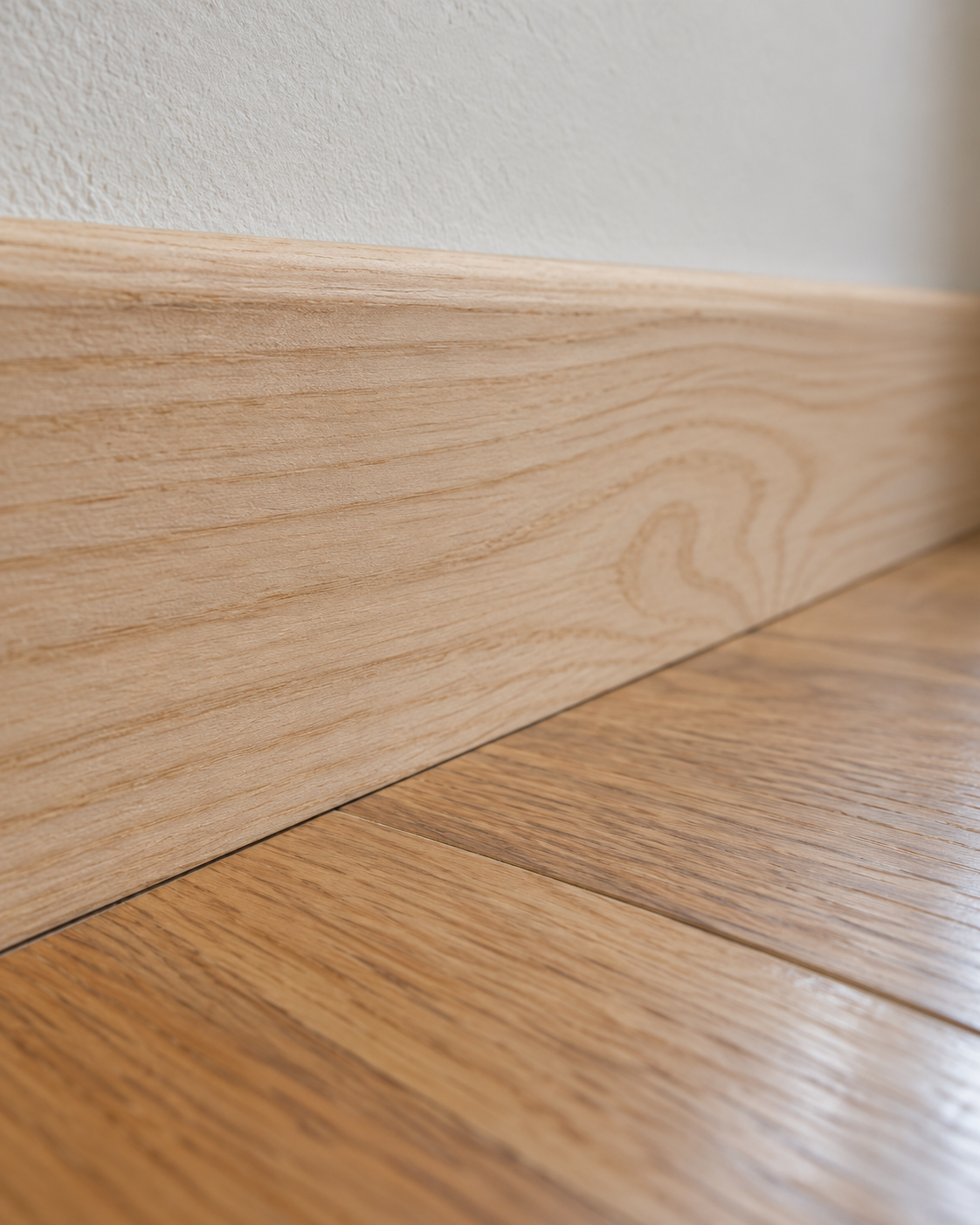 Close-up detail of a clean wooden baseboard seam along a bedroom floor.