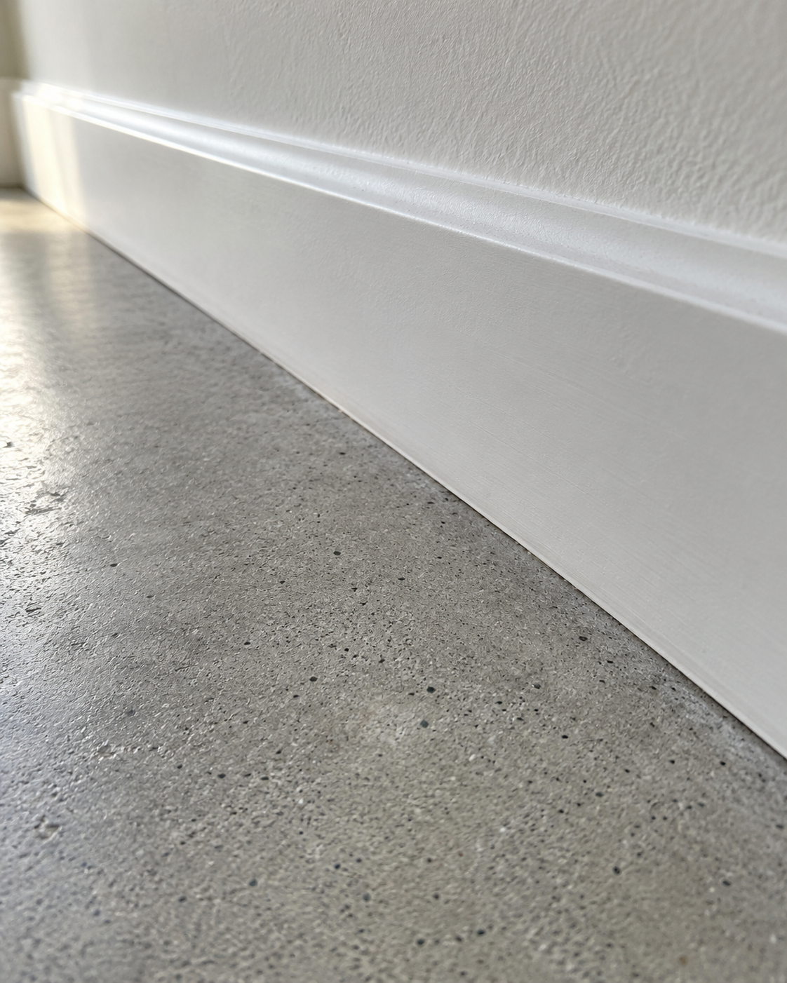 Close-up detail of a dry concrete subfloor and clean baseboard seam.