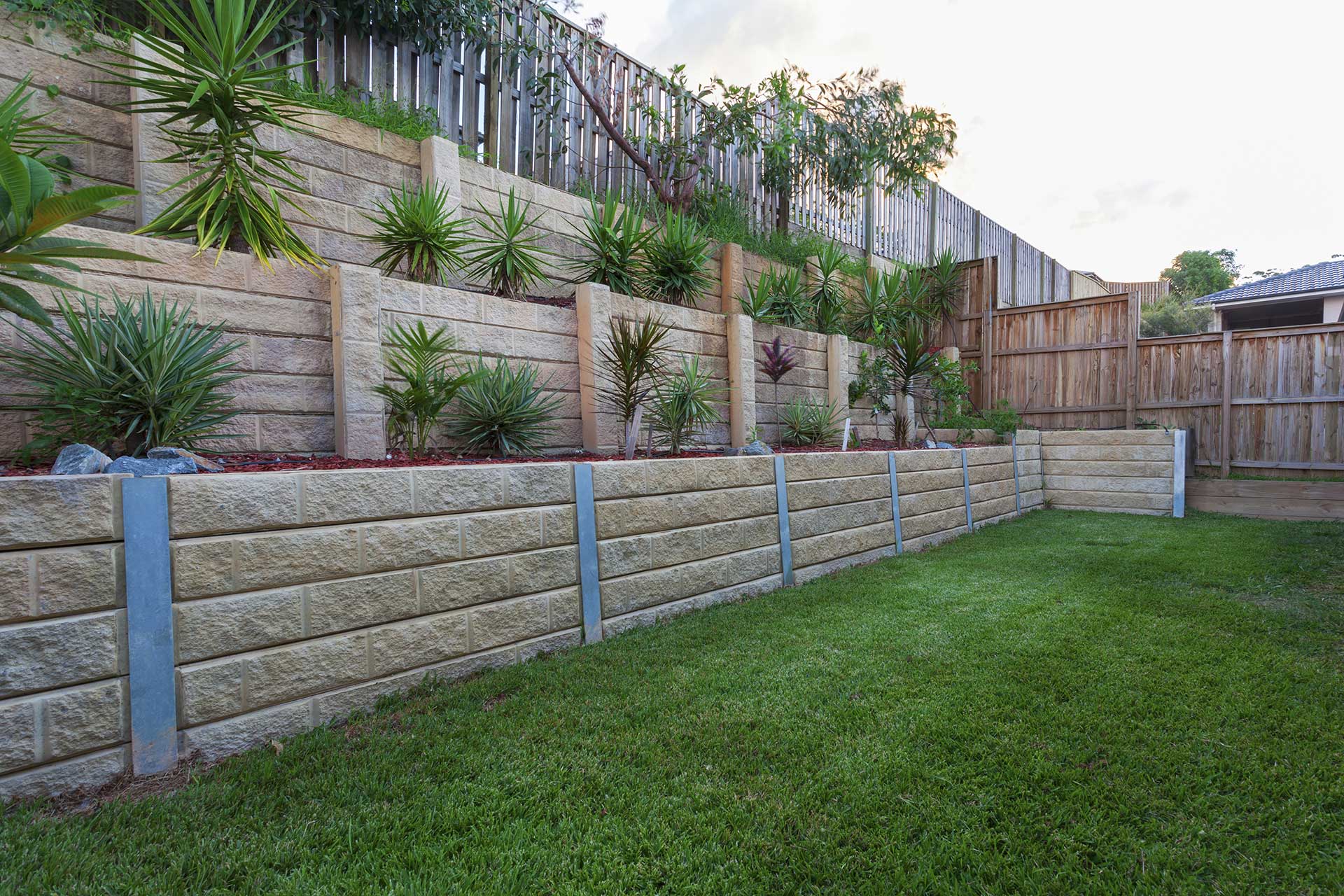 Natural stone retaining wall with garden beds over multiple levels