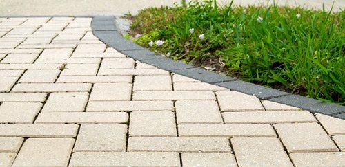 Sand coloured block paving close up with a small garden verge