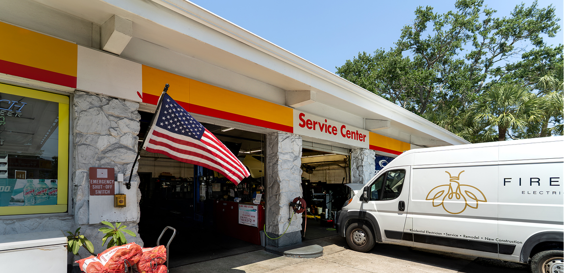 Shell service station with American flag, white van with logo, and 