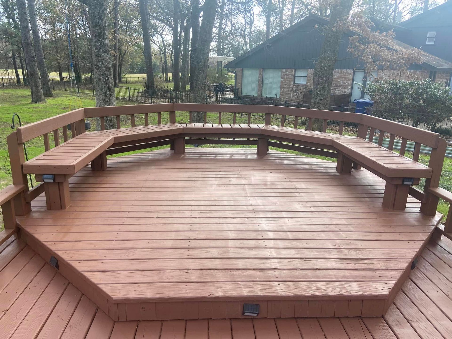 Wooden octagonal deck with built-in benches in a wooded backyard