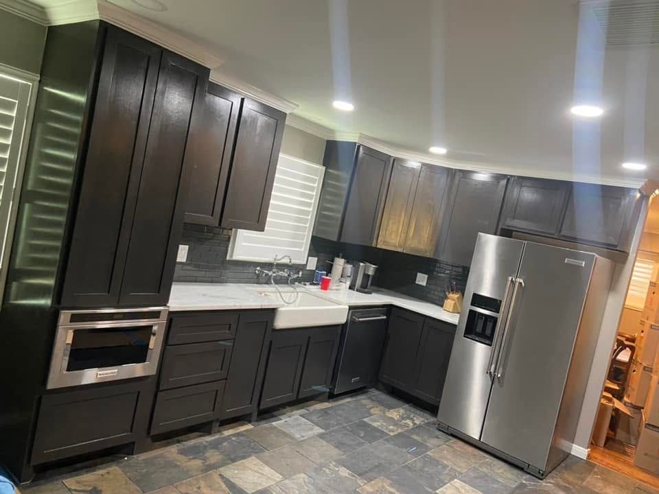 Modern kitchen with dark cabinets, stainless steel appliances, white countertops, and gray tile flooring.