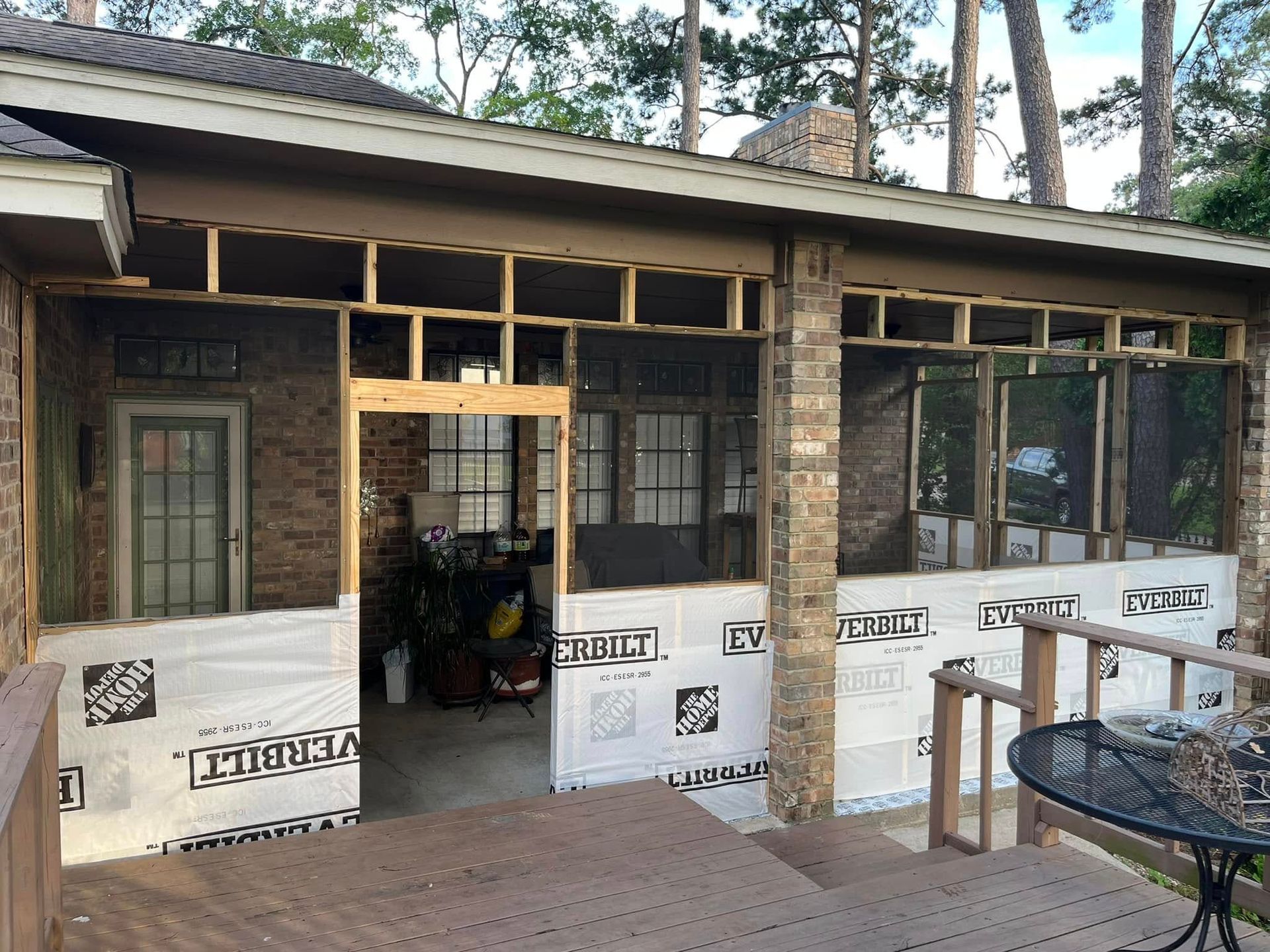 Partially renovated porch with exposed framing, white house wrap, and stone exterior walls