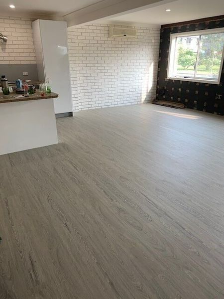 A Living Room With A Wooden Floor And White Brick Walls — Flooring Direct Mid North Coast in South Kempsey, NSW