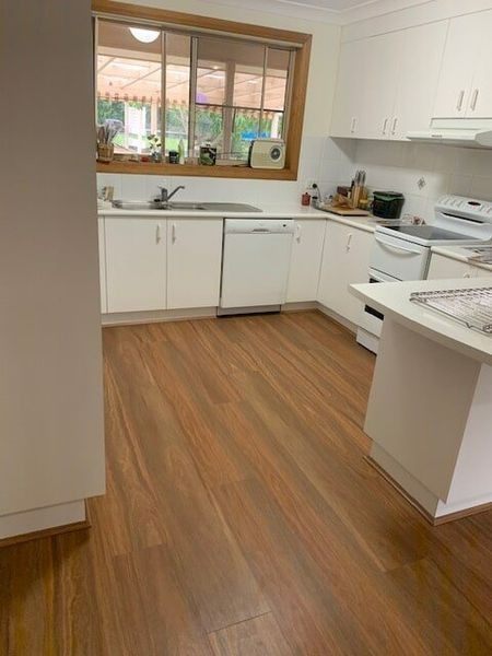 An Empty Kitchen With Wooden Floors And White Cabinets — Flooring Direct Mid North Coast in South Kempsey, NSW