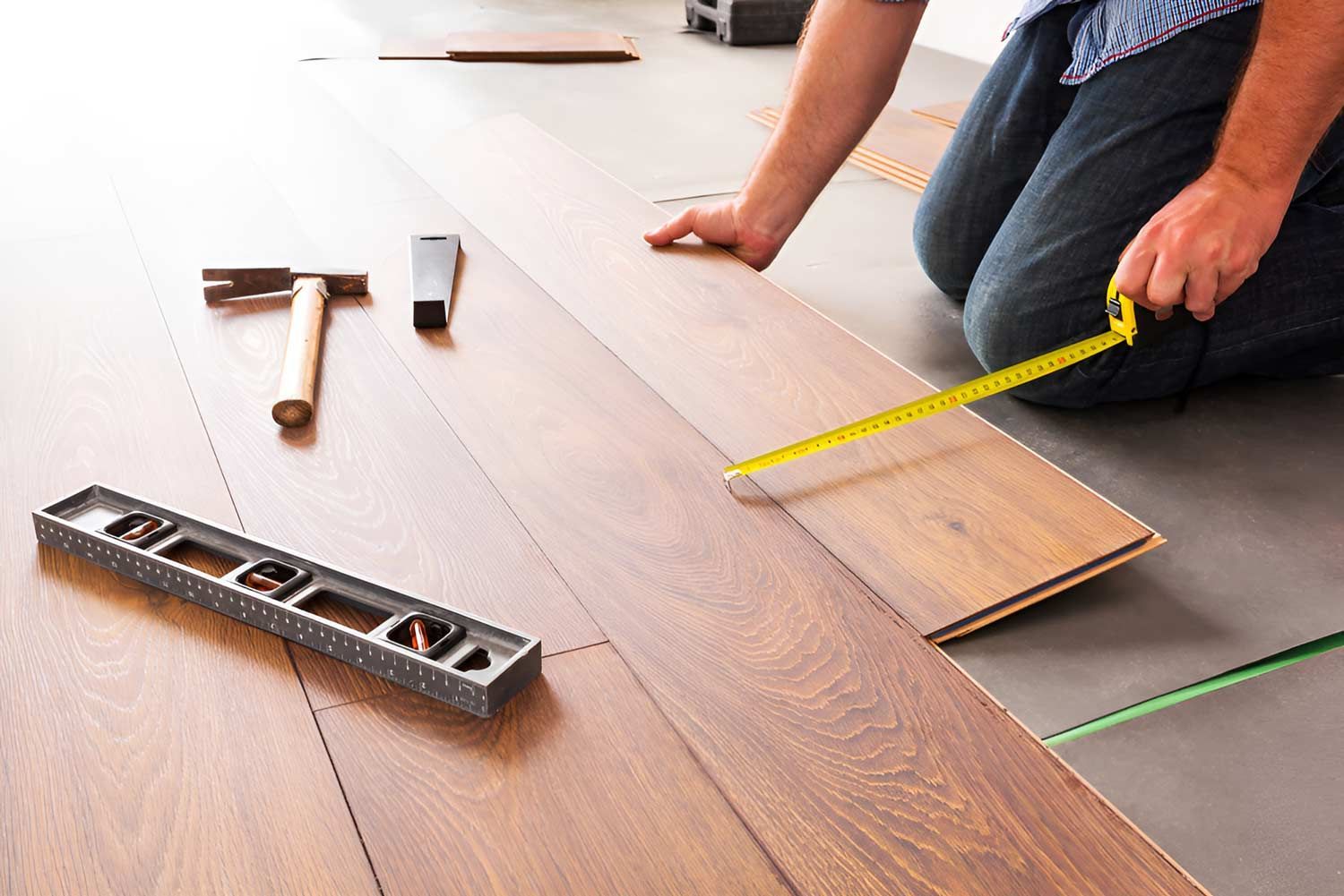 Man Installing New Laminated Wooden Floor — Flooring Direct Mid North Coast in Kempsey, NSW